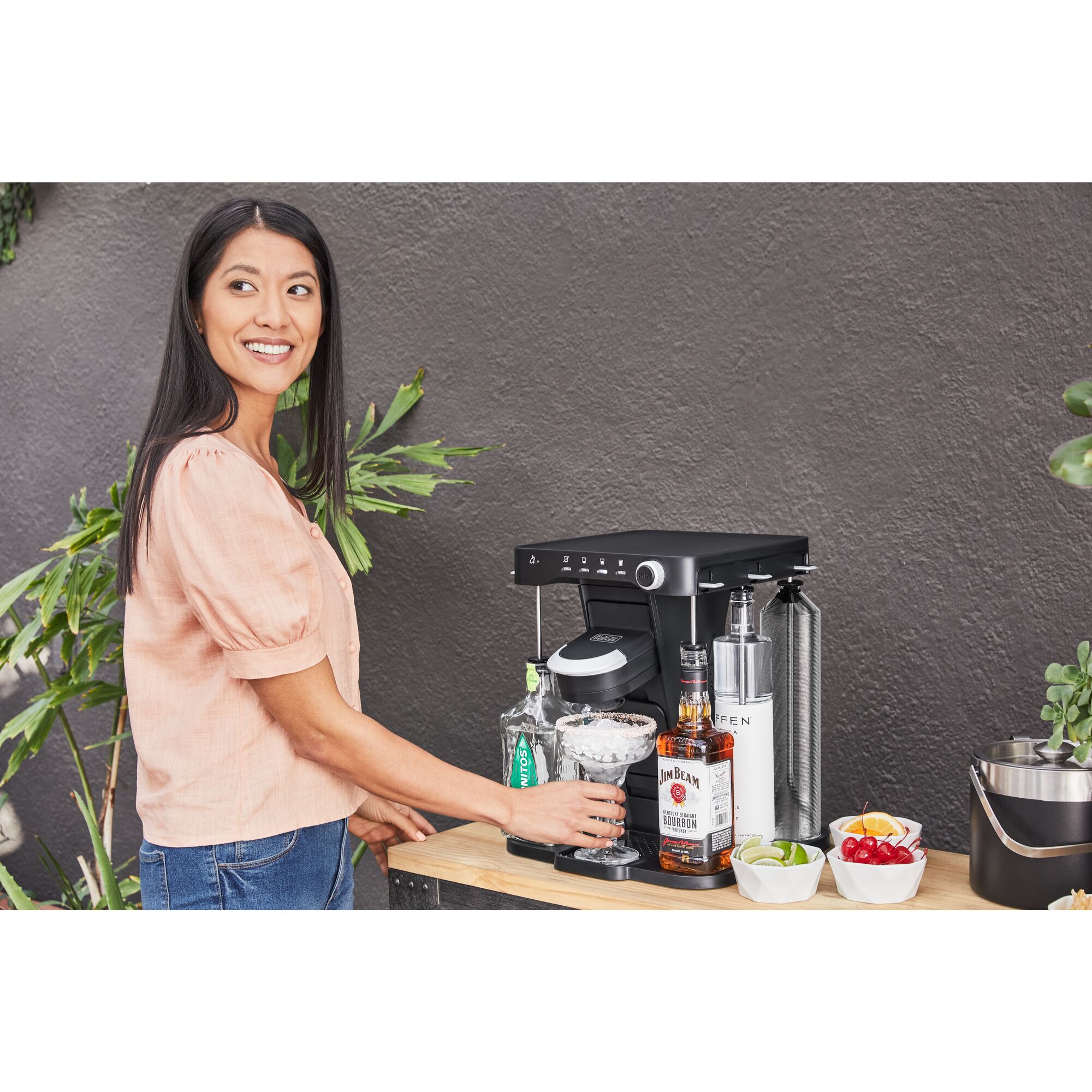 woman, on the patio, placing her ice filled margarita glass onto the bev by BLACK+DECKER\u2122 cocktail maker
