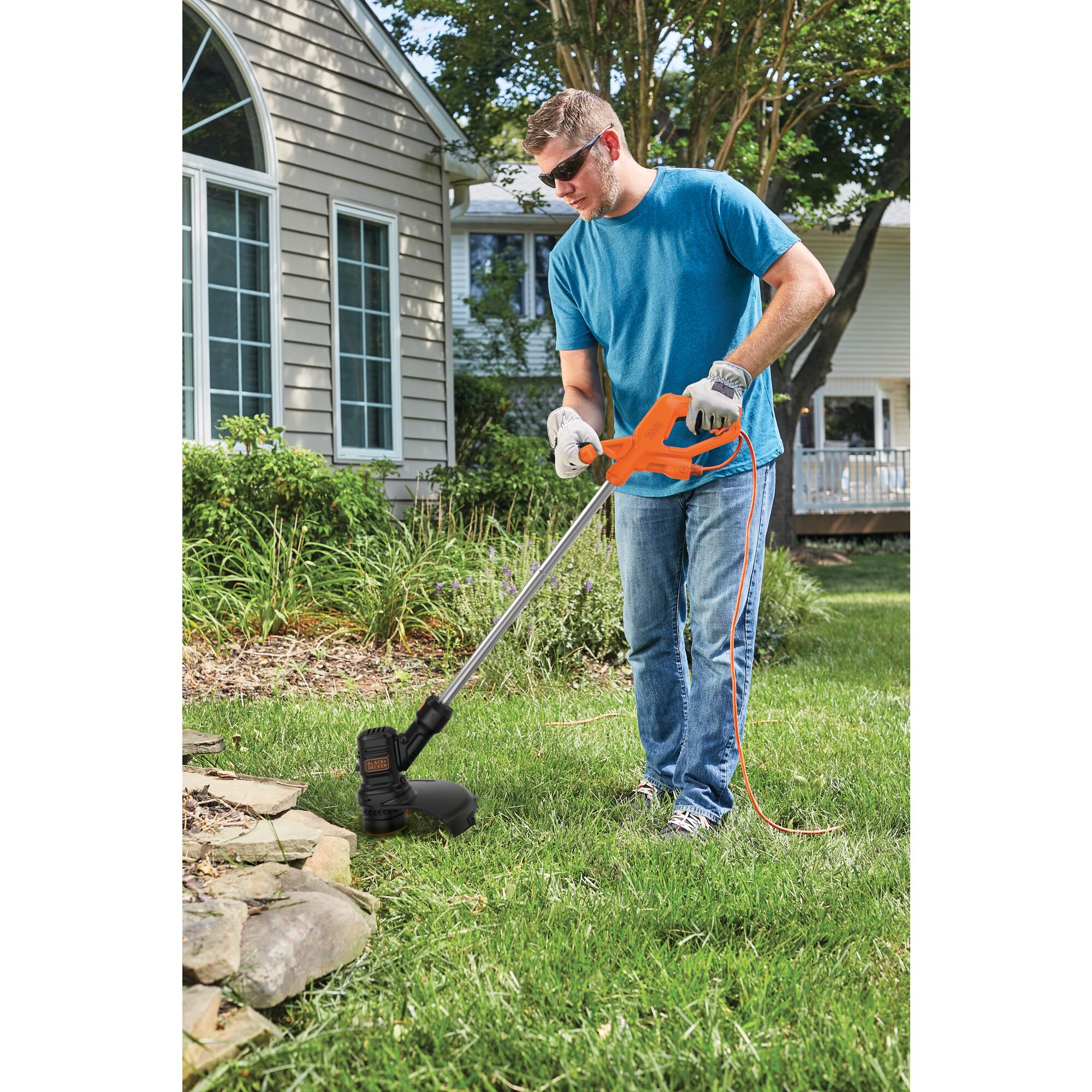 Electric string trimmer being used by a person to trim grass.\n