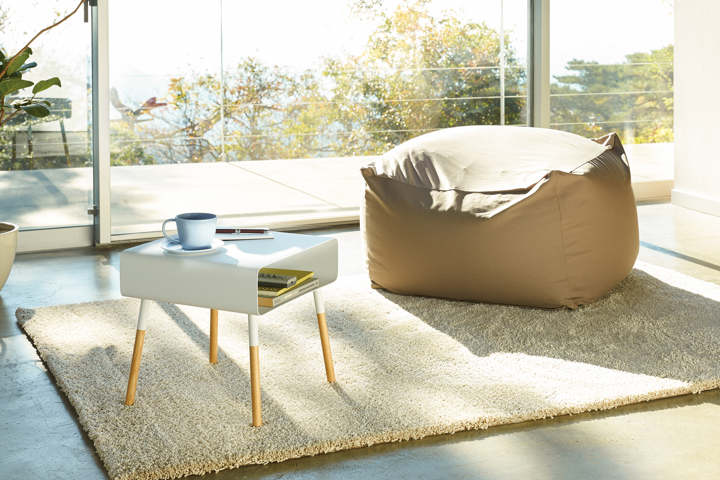 White Short Storage Table holding books and phone in living room by Yamazaki Home.