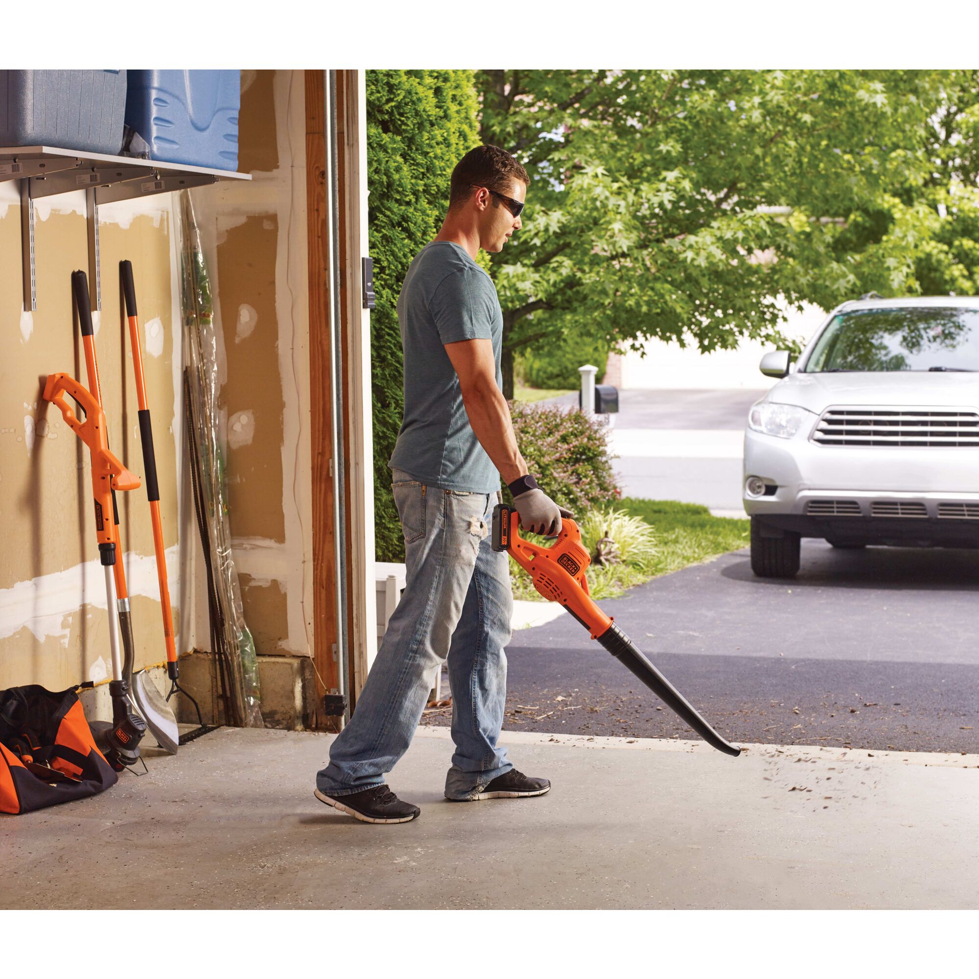 Man using 20V Max Lithium Sweeper to clear debris from a garage.