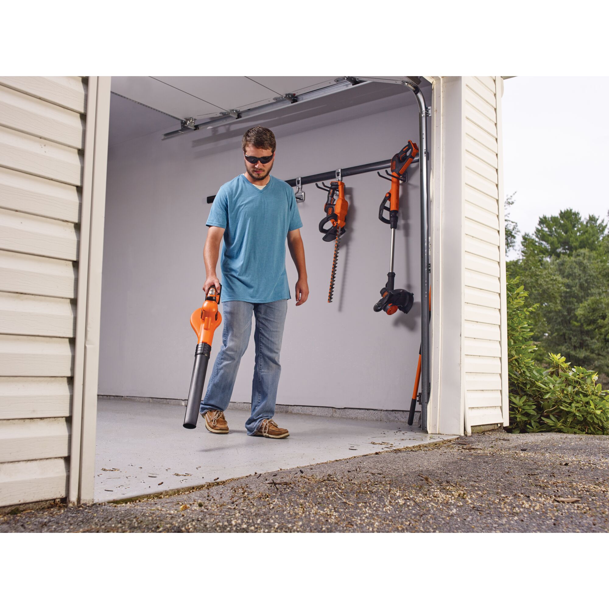 Man clearing debris from a garage with the 20V Max Lithium Powerboost Sweeper.