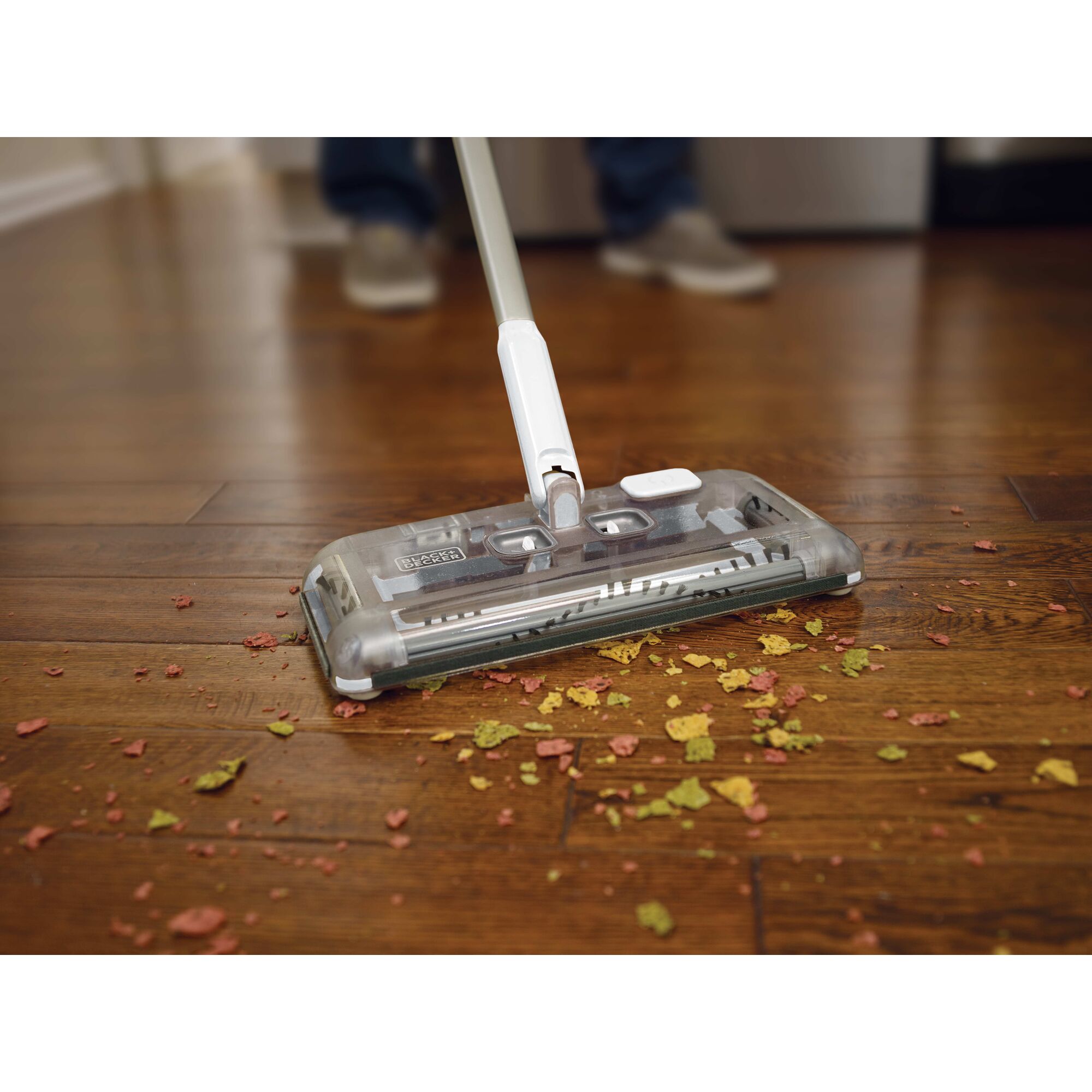 Person cleaning floor with floor sweeper