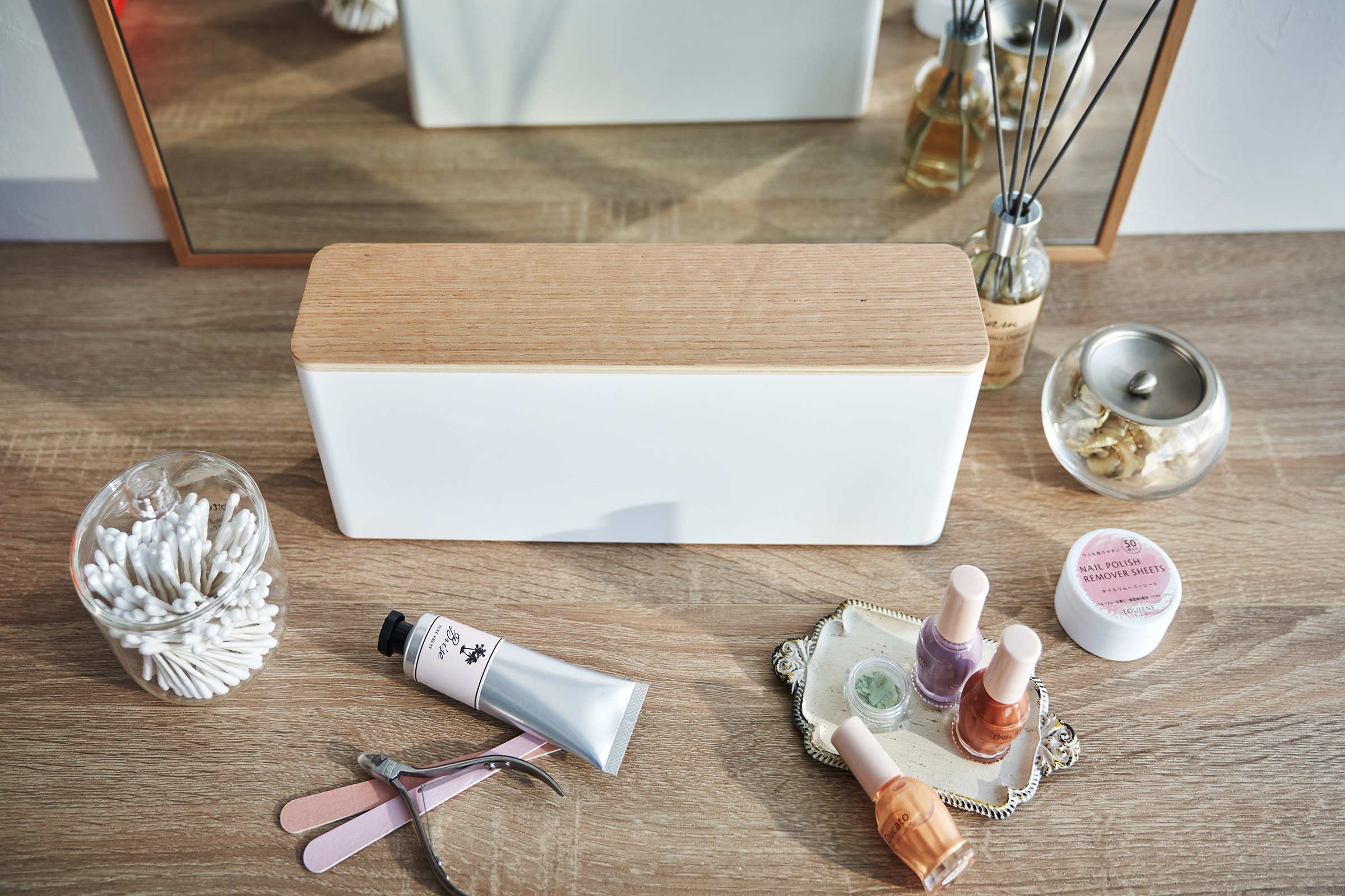 A Yamazaki Nail Polish Organizer sitting on a table near various nail accessories.