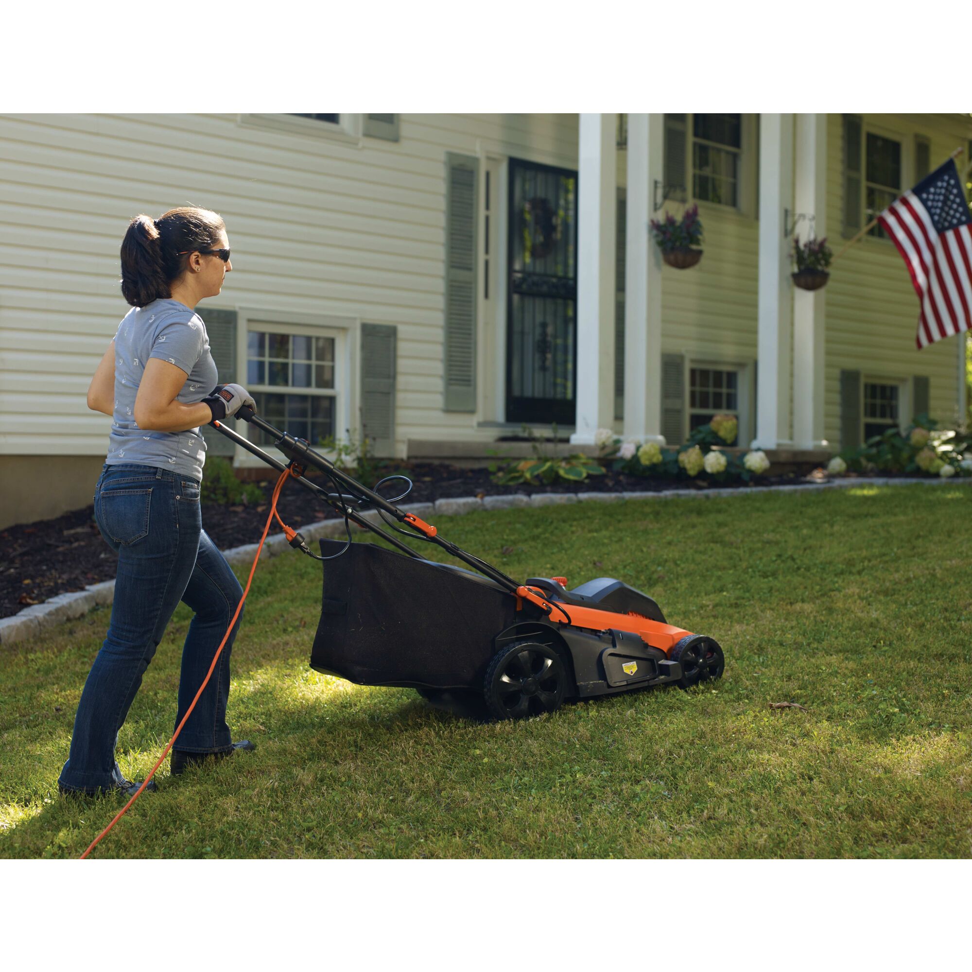 Woman pushing Corded Lawn Mower up a hill.