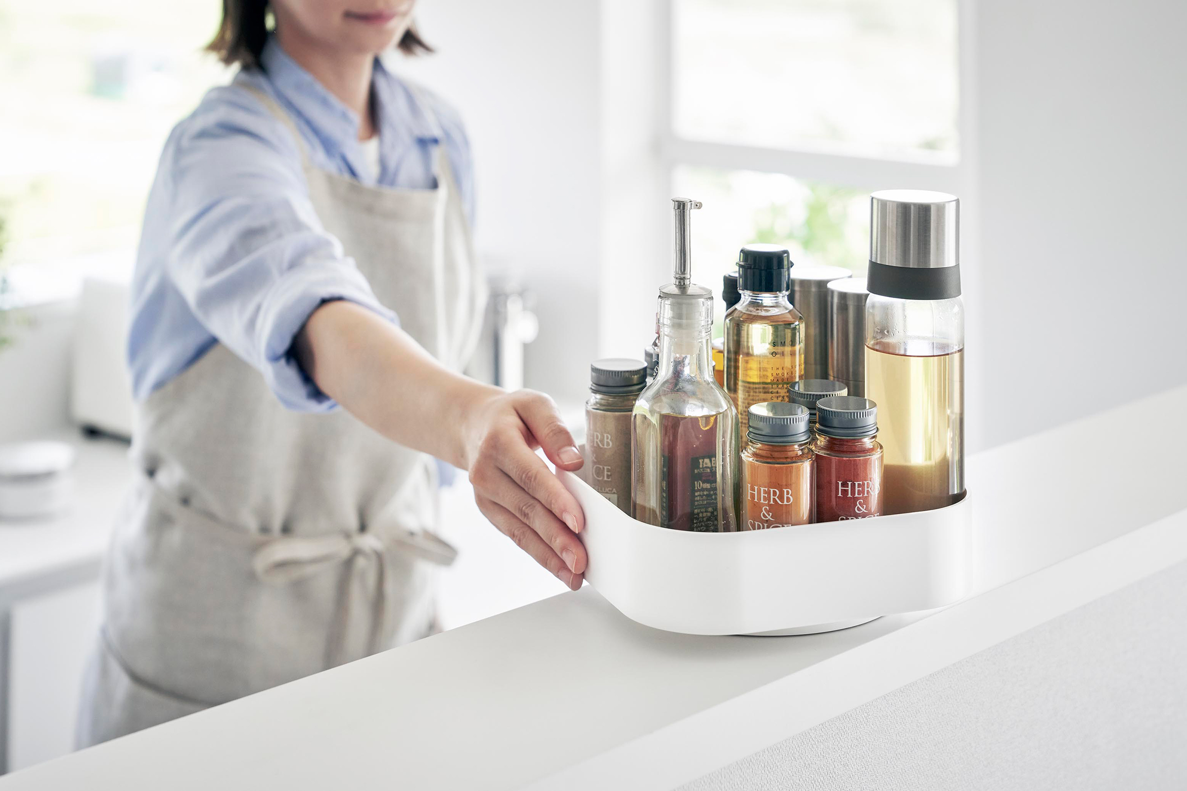 White Yamazaki Home Rotating Storage Tray with spices and oil stored being turned.