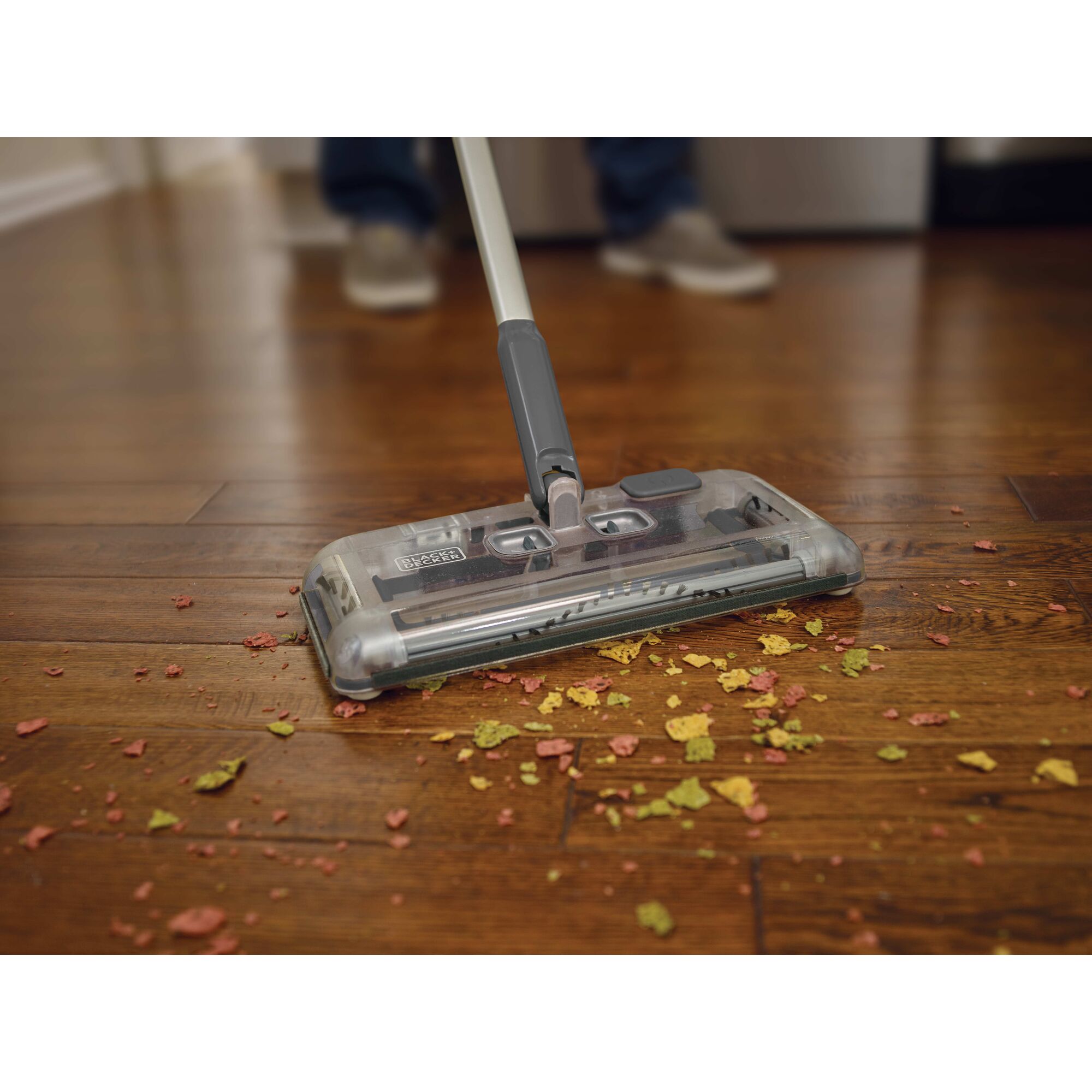 Person cleaning floor with floor sweeper