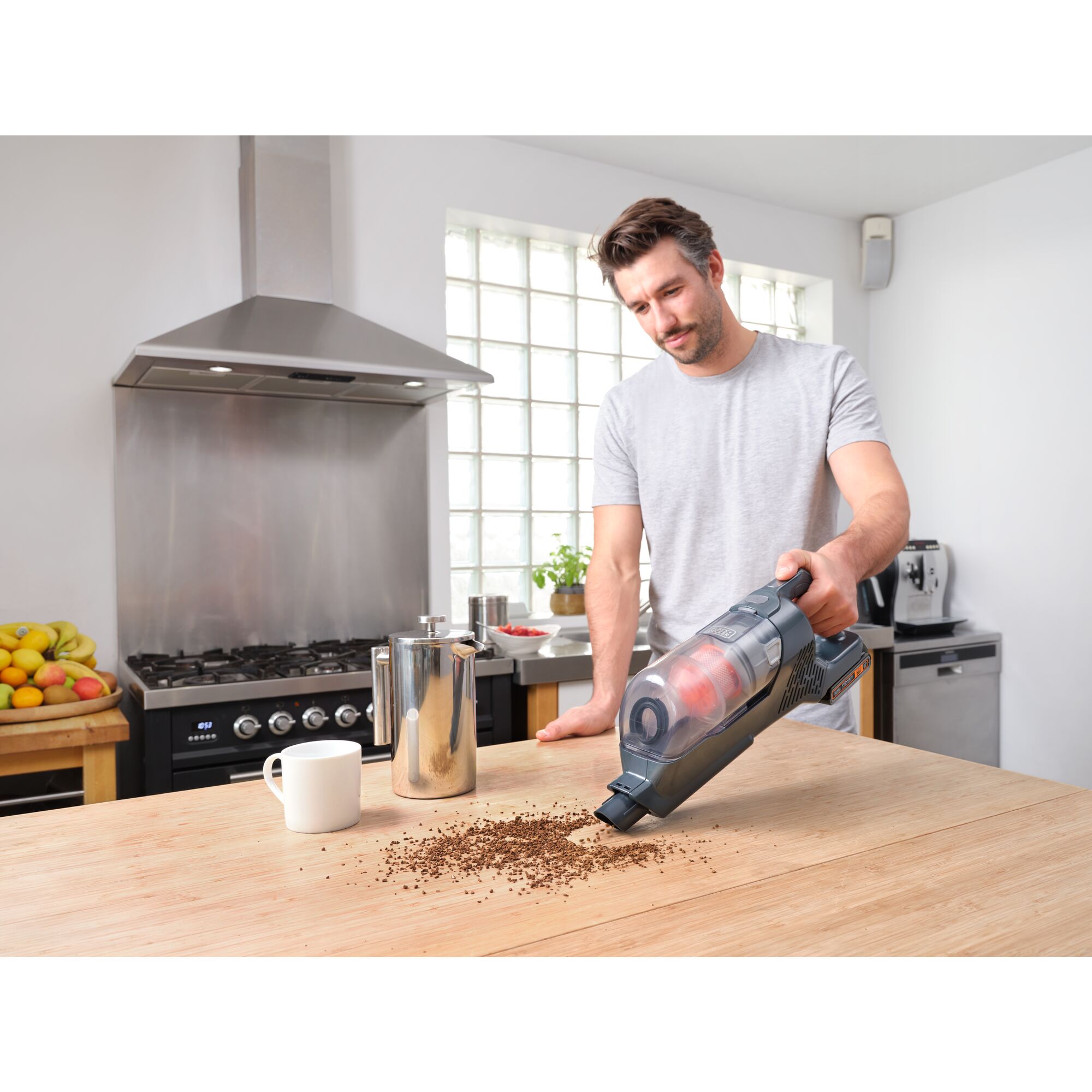 POWER SERIES plus Cordless Stick Vacuum being used to clean coffee powder from counter table.