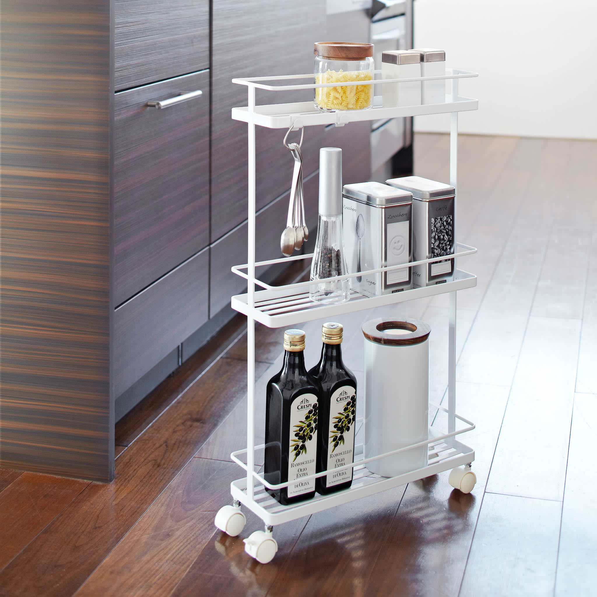 Vorderansicht des weißen Rollwagens von Yamazaki Home mit Gewürzen, Ölen und Kochzubehör in der Küche.
