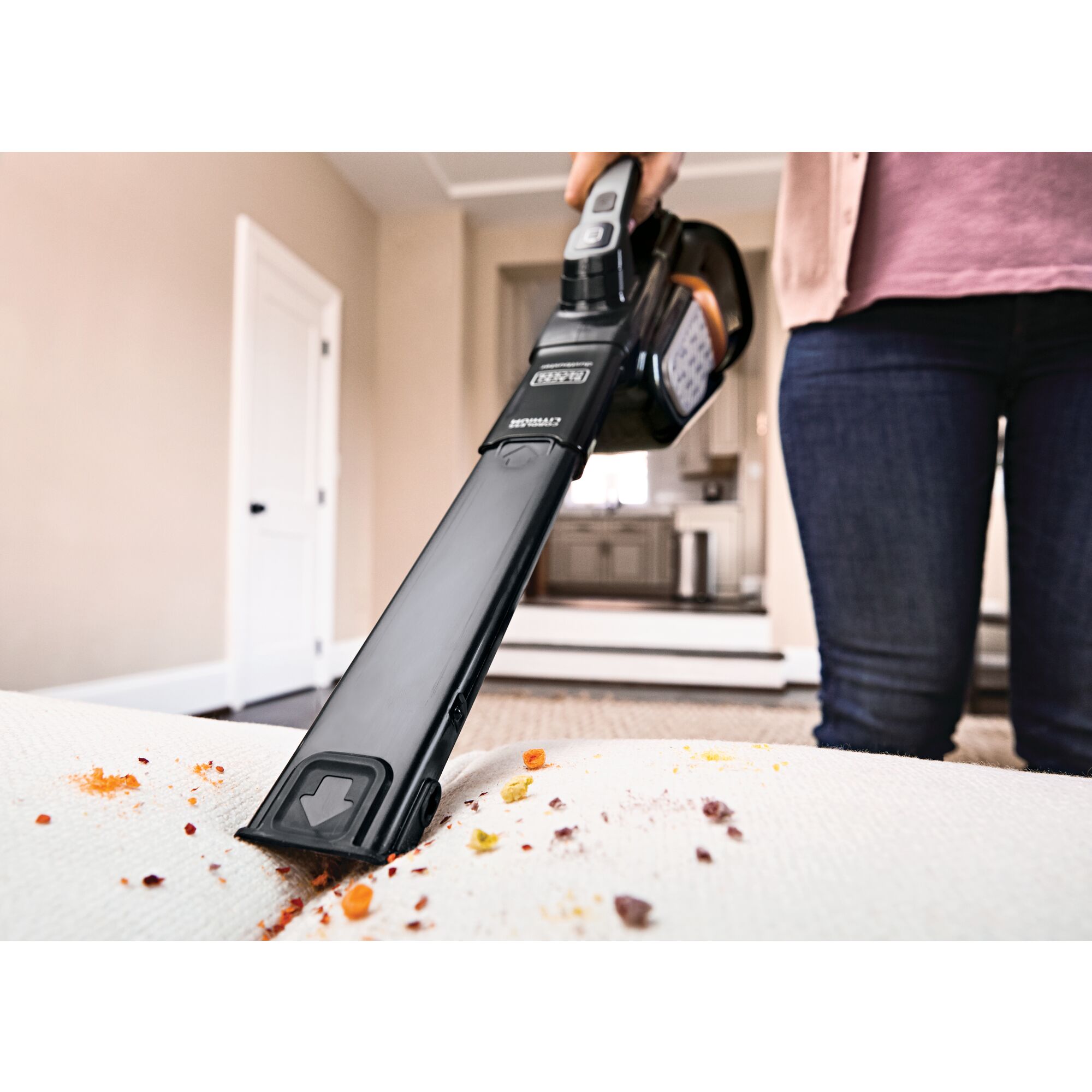 MAX Dustbuster Advanced Clean plus Cordless Hand Vacuum being used to clean messy sofa.