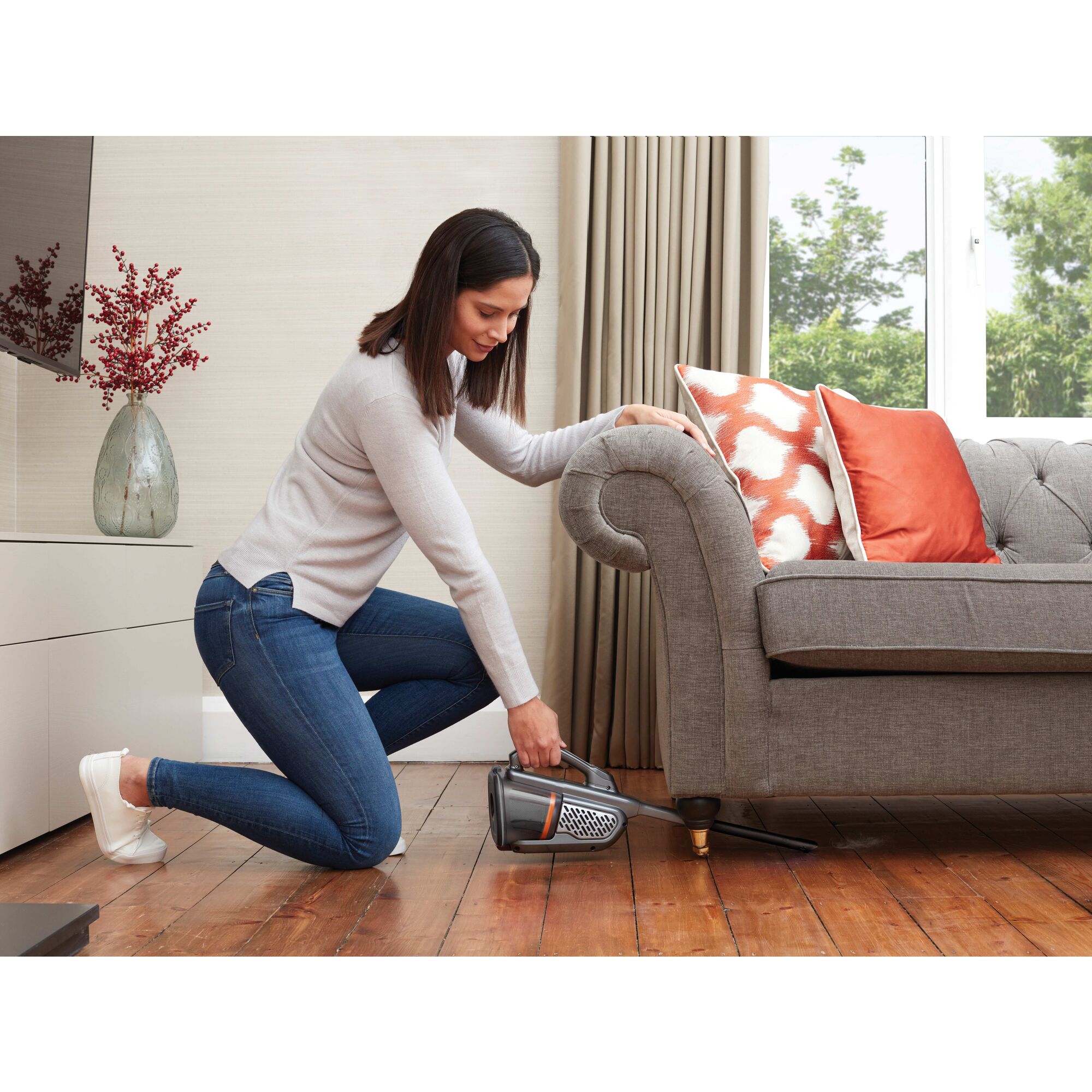 Dustbuster AdvancedClean plus Hand Vacuum being used by person to clean floor under couch.