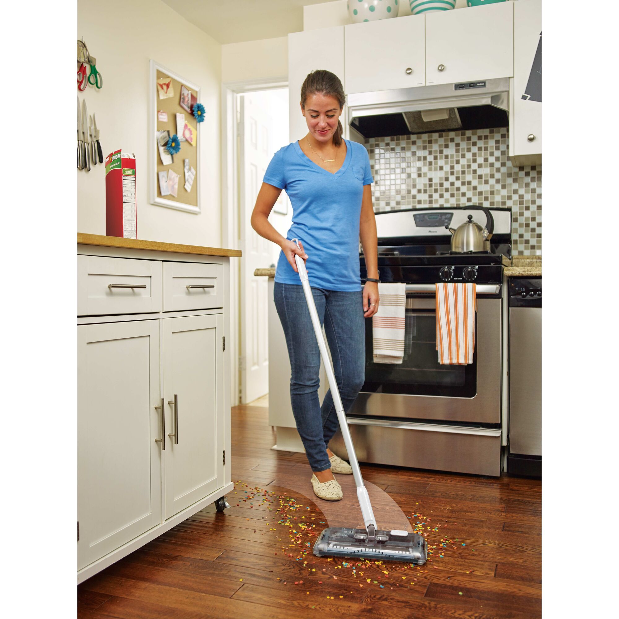 Person using black and decker 50 Minute Powered Floor Sweeper to clean debris off of a wooden kitchen floor