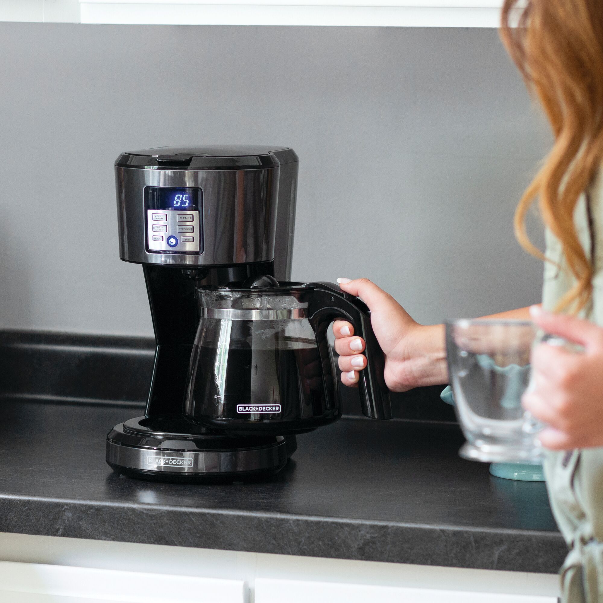 12 Cup Coffeemaker Programmable Exclusive VORTEX Technology being used to make coffee by a person.