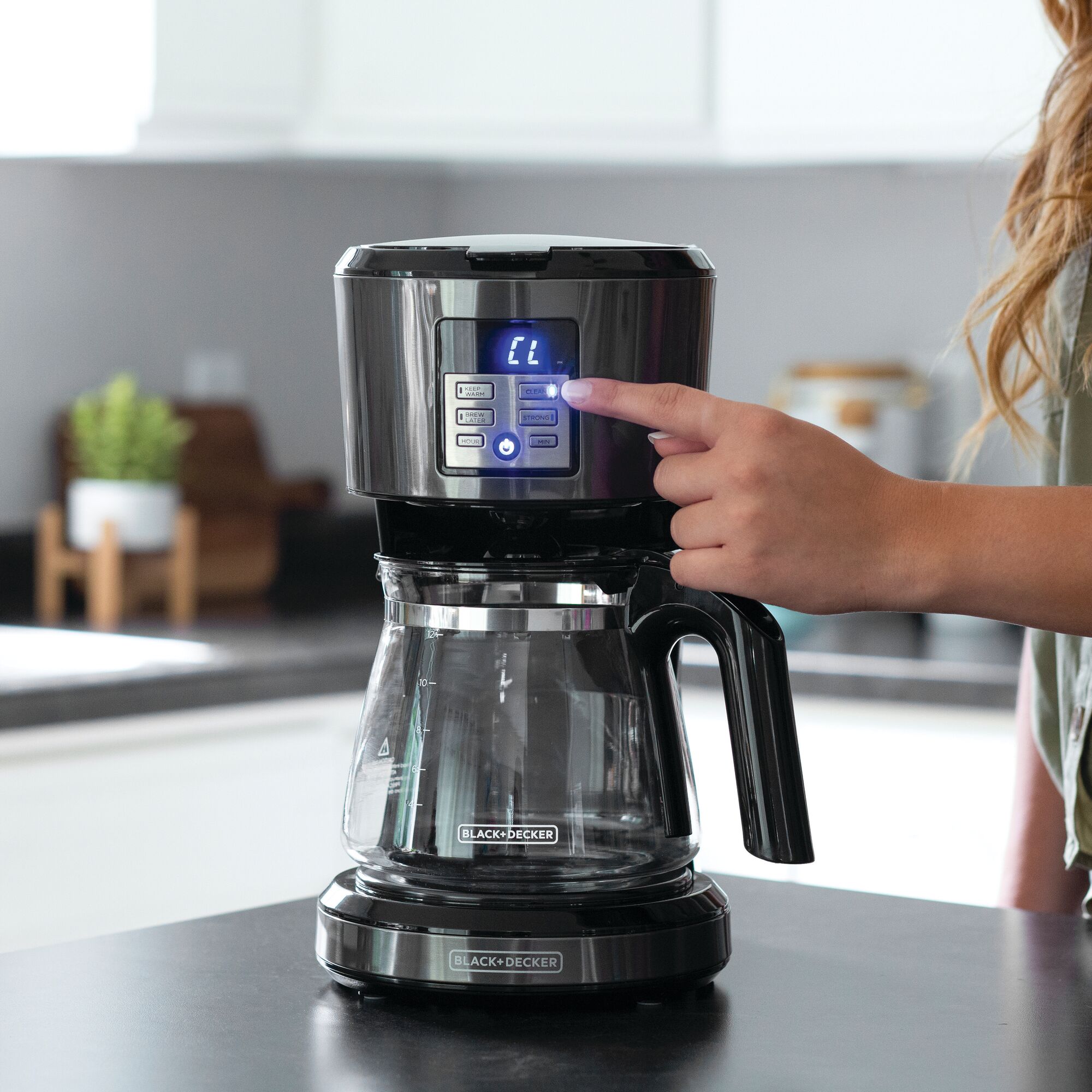 Person pushing the controls on the BLACK+DECKER coffee maker