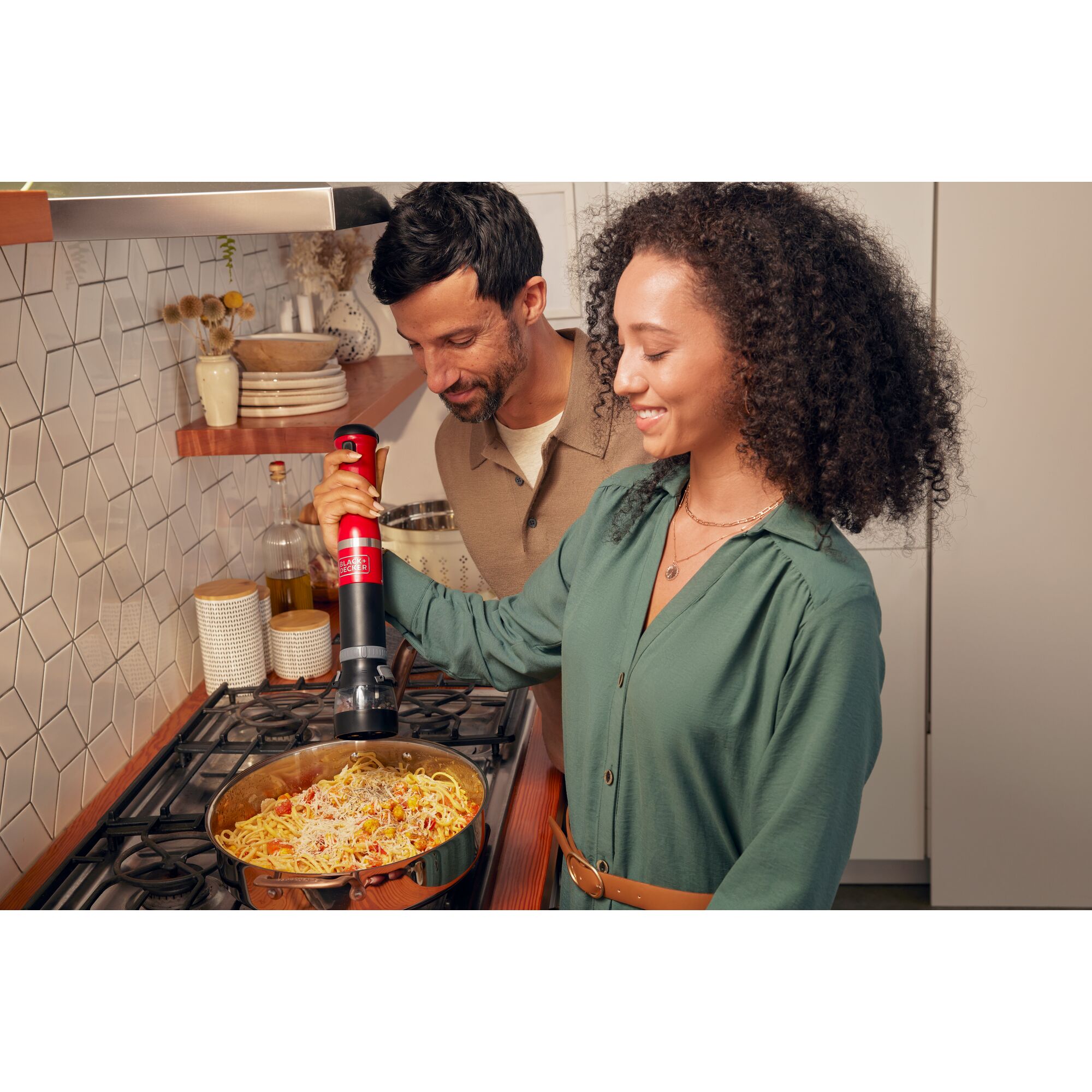 Talent using the red, BLACK+DECKER kitchen wand spice grinder to add spices to a pasta entr\xe9e