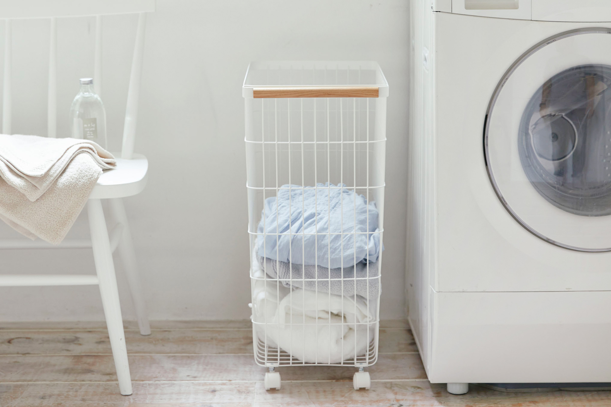 Yamazaki Home Rolling Wire Basket filled with laundry beside a washing machine