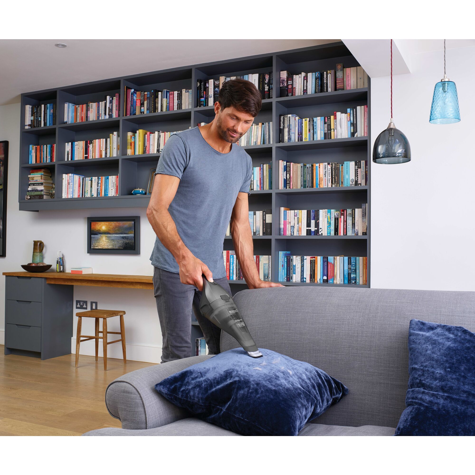 Man cleaning sofa cushion with dustbuster handheld vacuum