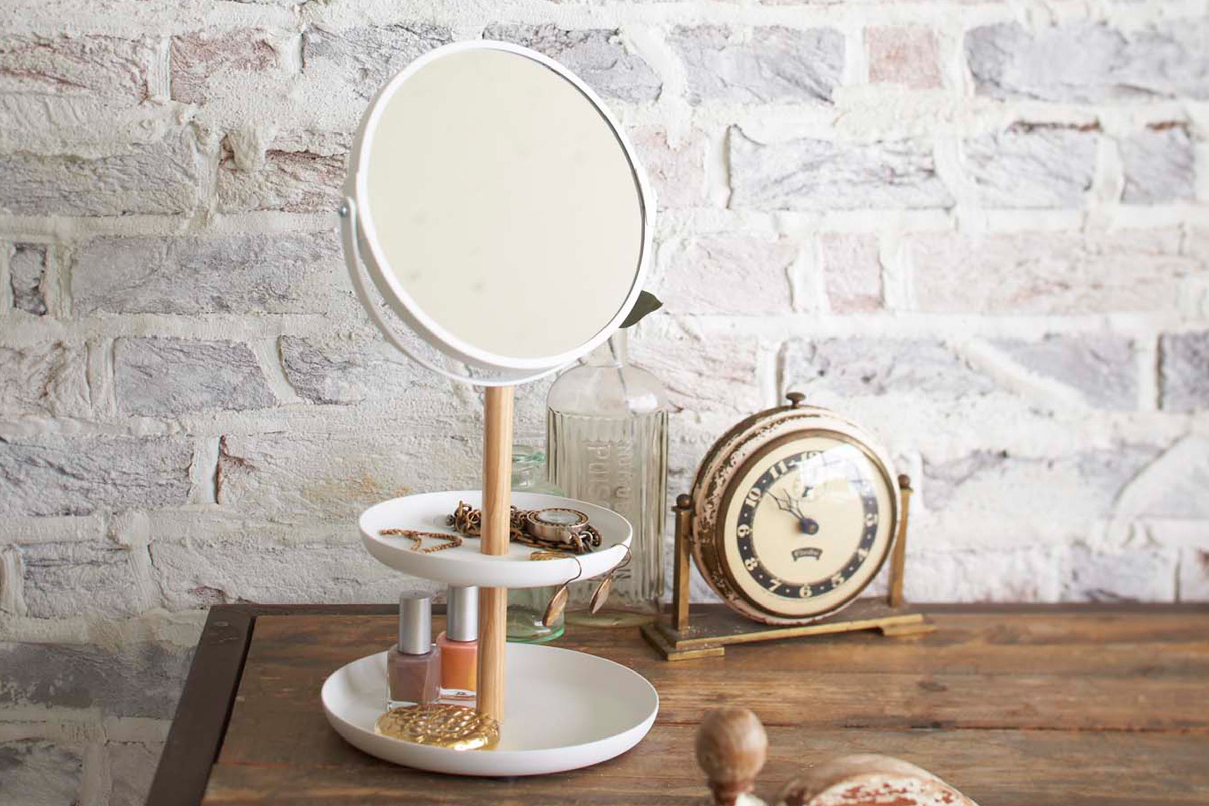 Yamazaki's Tabletop round mirror with tiered trays holding accessories on a dresser.