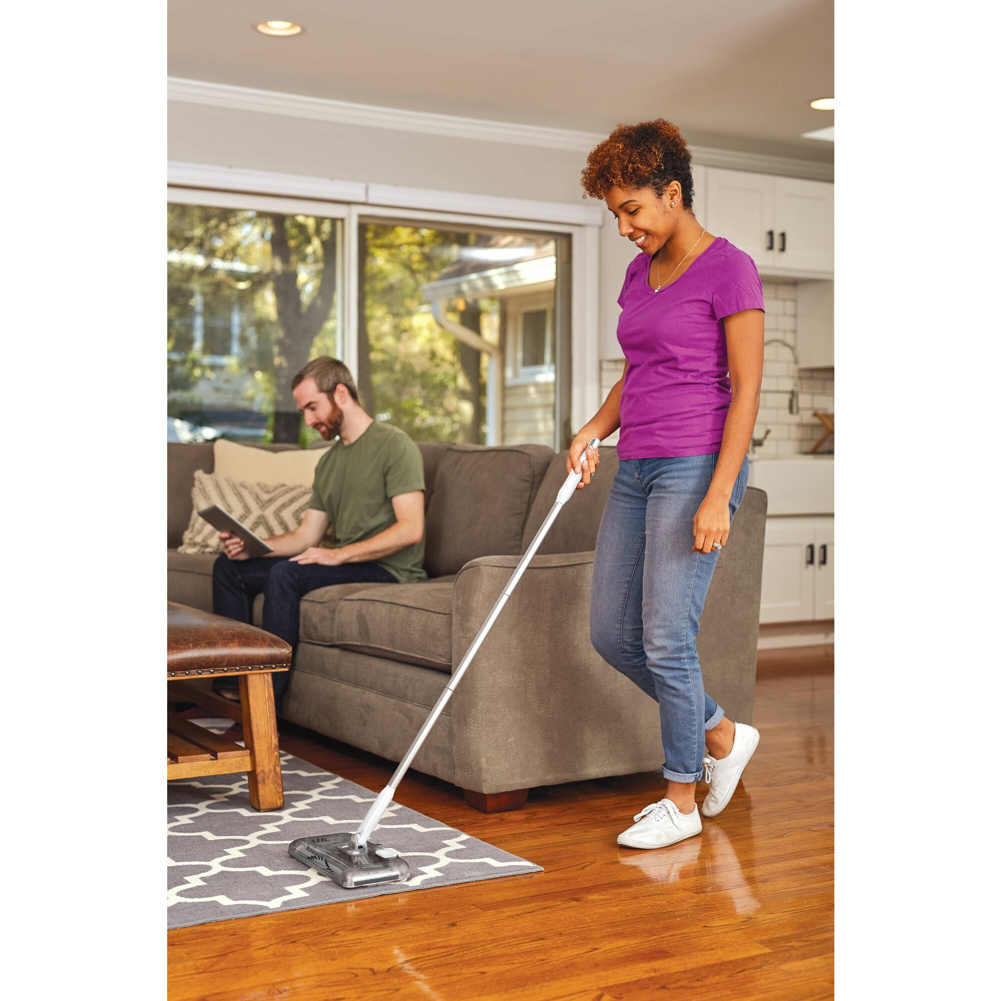 Person using black and decker 50 Minute Powered Floor Sweeper to clean a rug in a living room