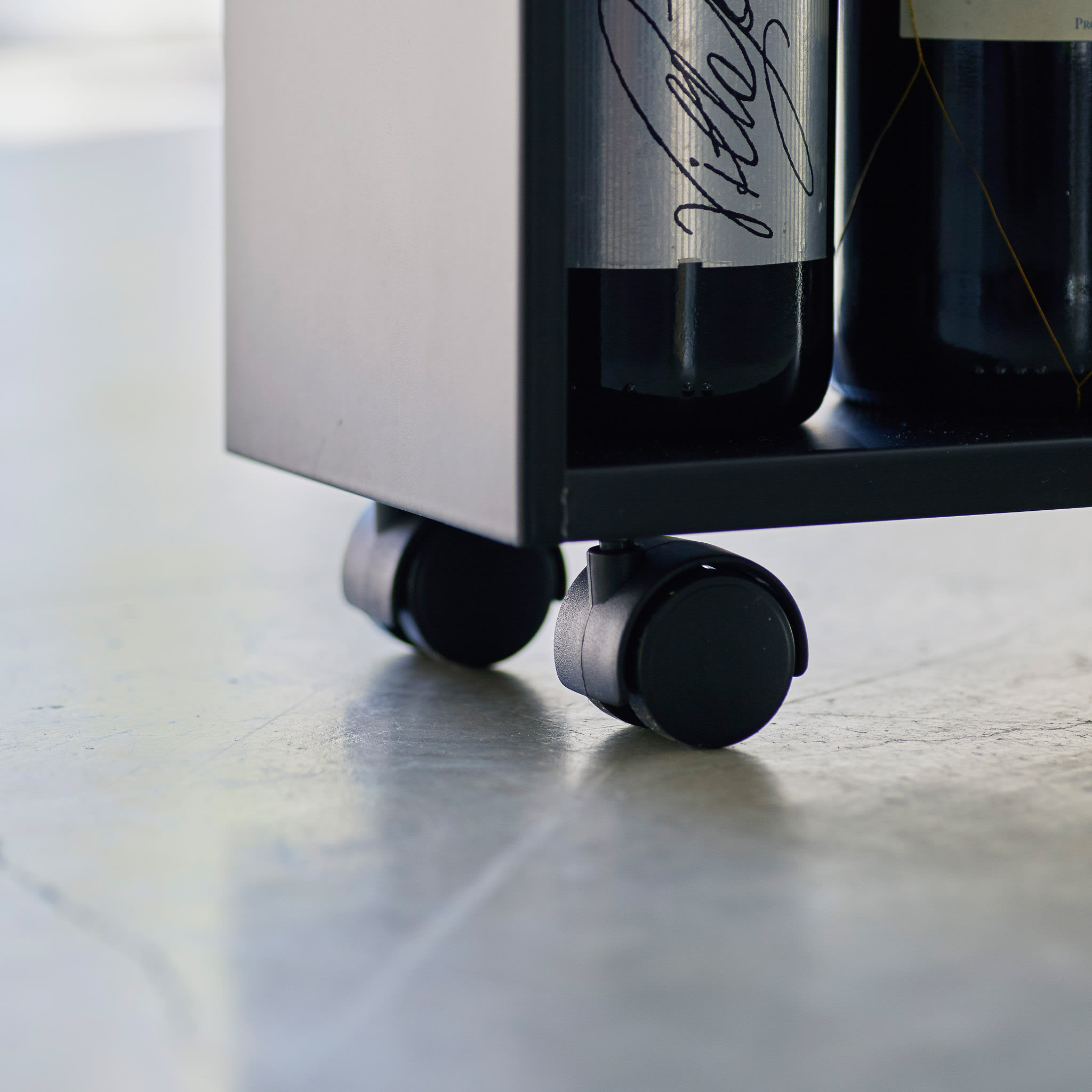 Nahaufnahme der Frontansicht des weißen rollenden Aufbewahrungswagens von Yamazaki Home, der am Griff gehalten wird und Gewürze und Zutaten in der Küche aufbewahrt.