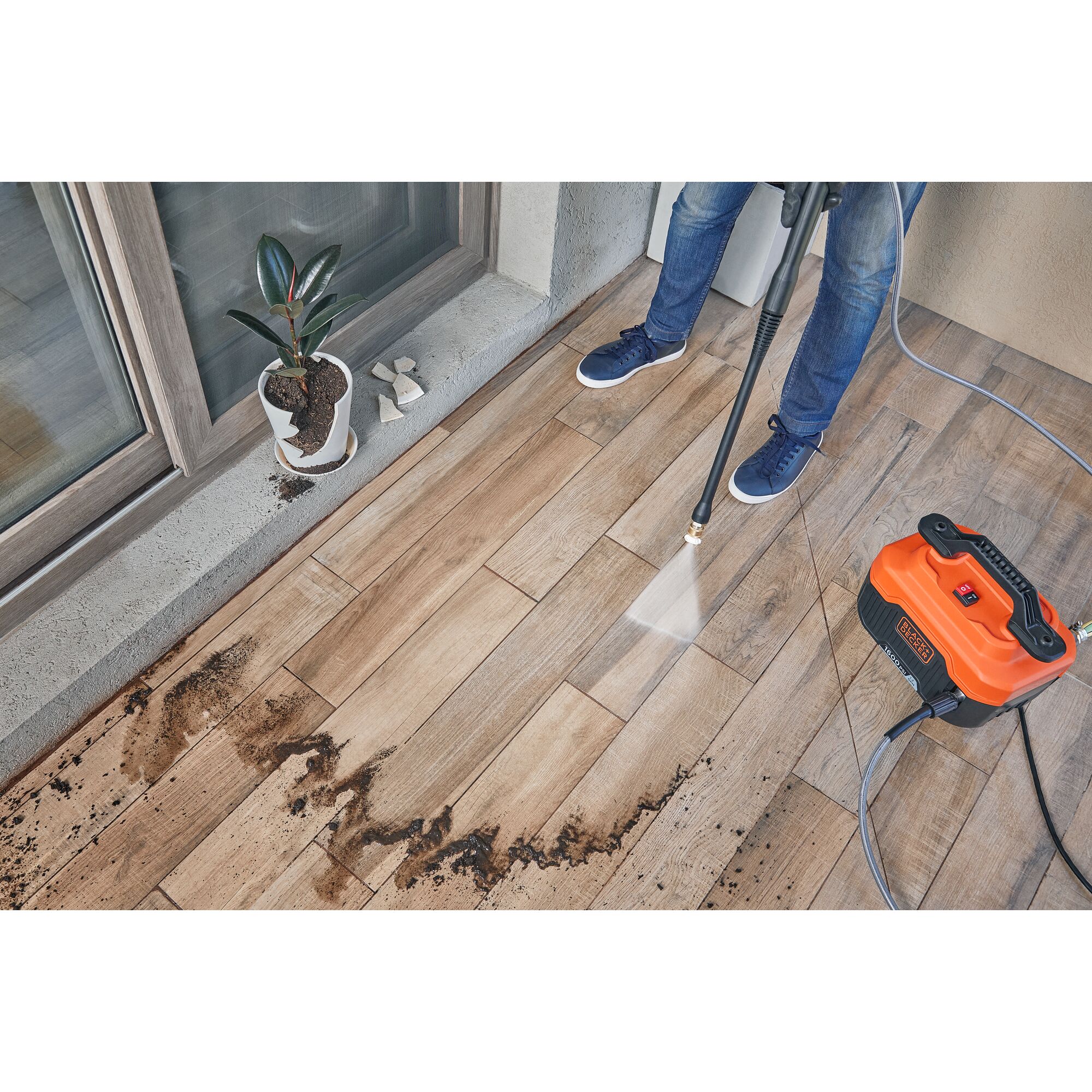 Person shown from waist down using BLACK+DECKER 1,600 MAX* psi pressure washer with the 40\u02da nozzle to clean dirt off patio