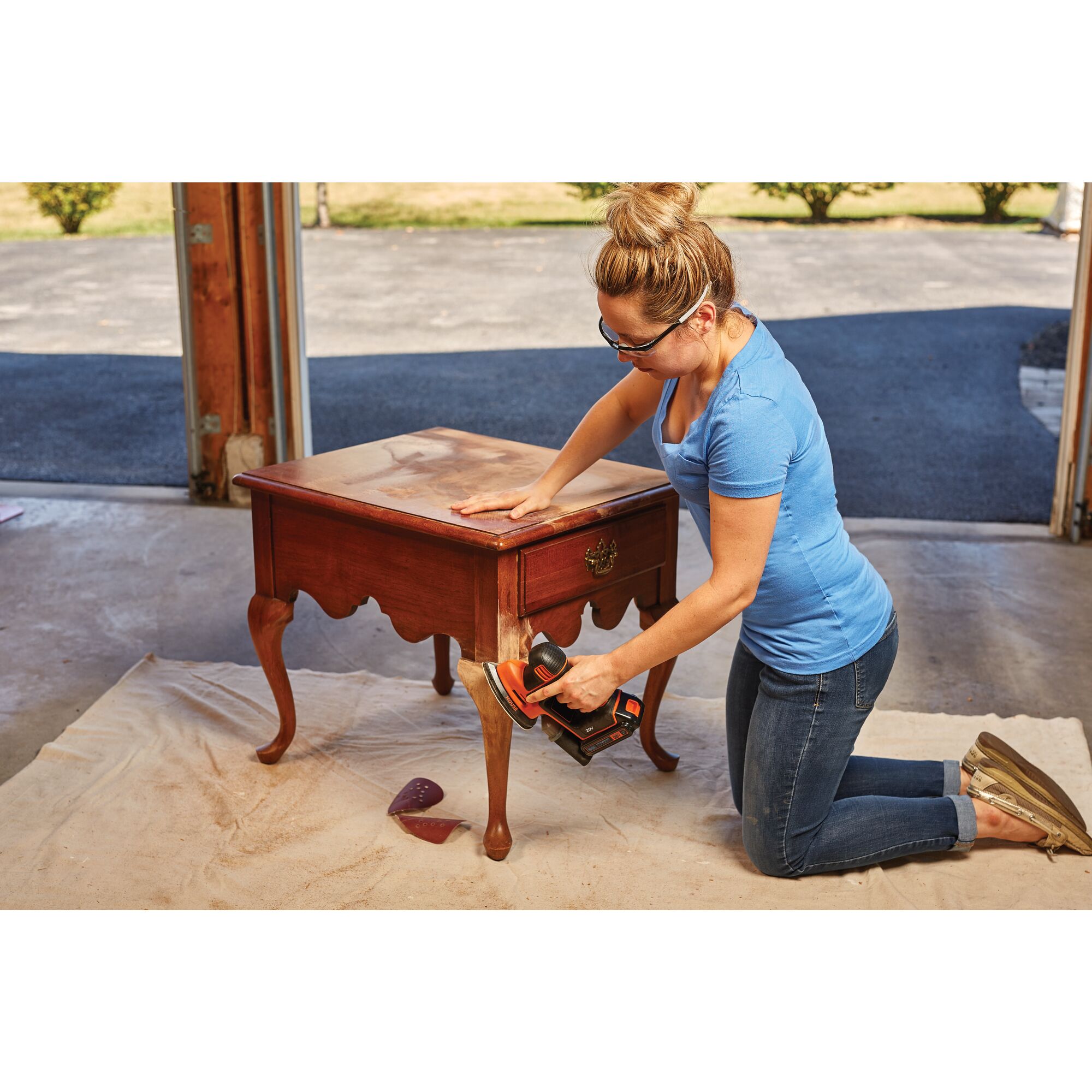 20 volt max cordless mous sander being used by a person to remove finish from a wooden side table