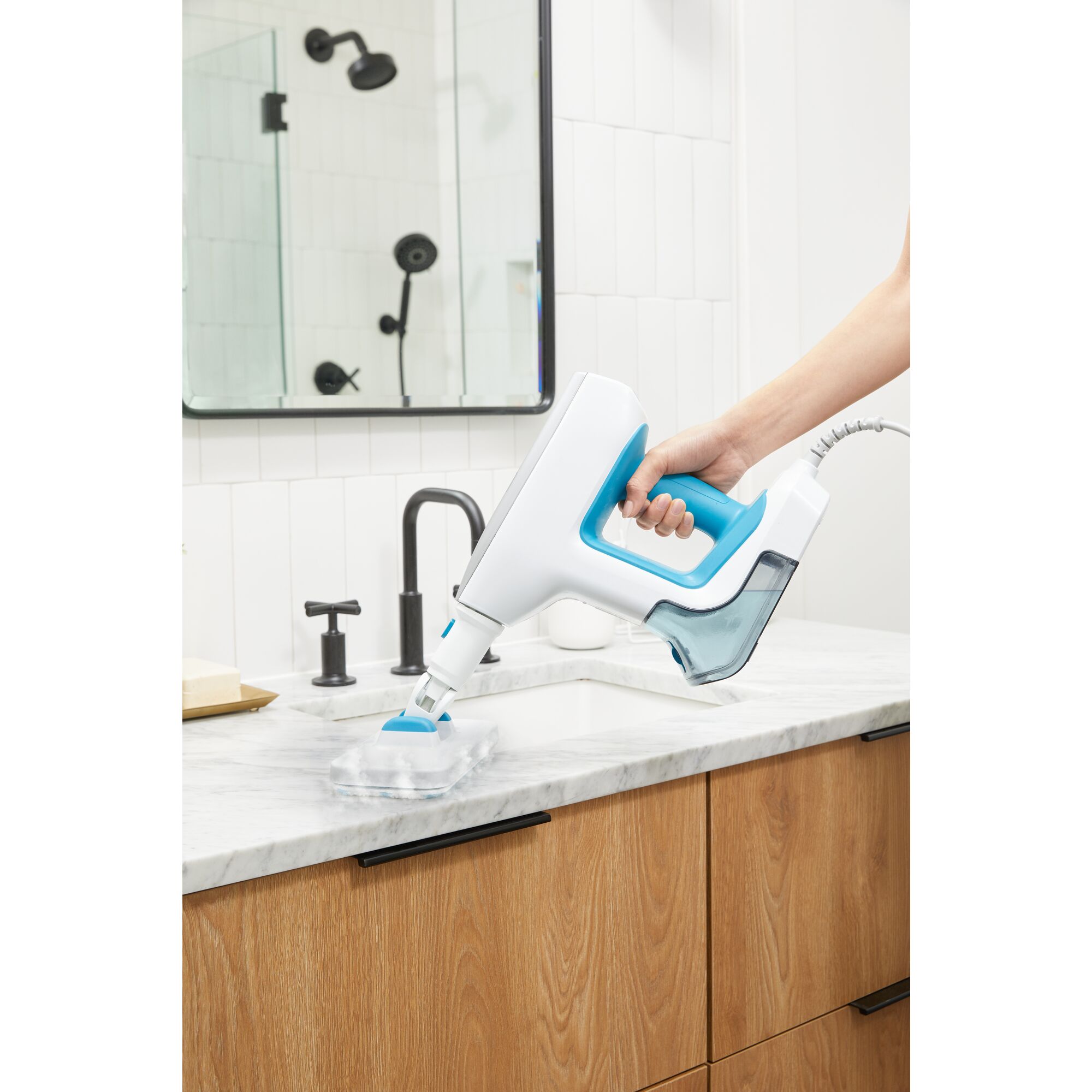 Woman cleaning bathroom countertop with steam mop accessory