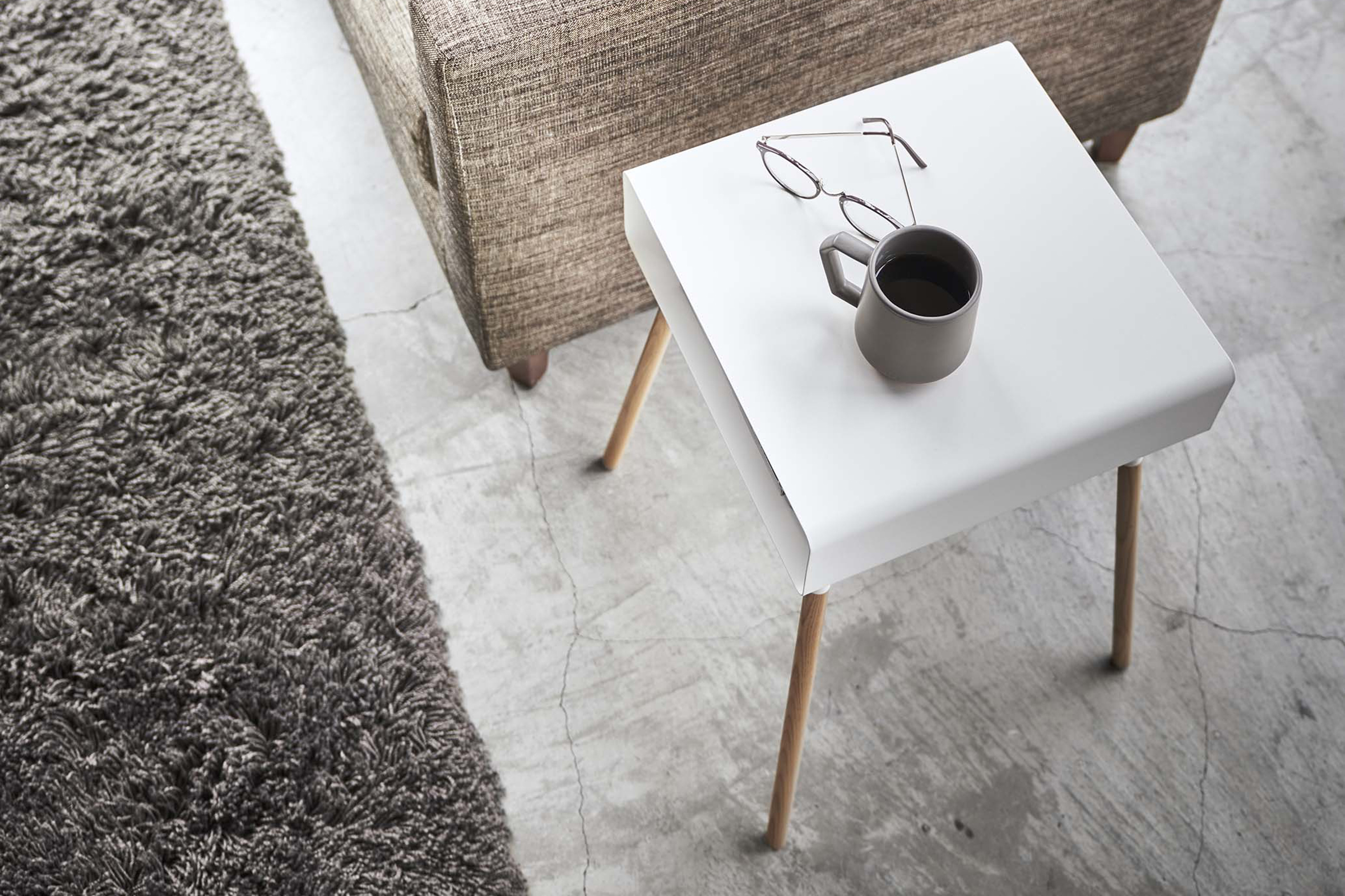 Aerial view of white Storage Table holding glasses and coffee in living room by Yamazaki Home.