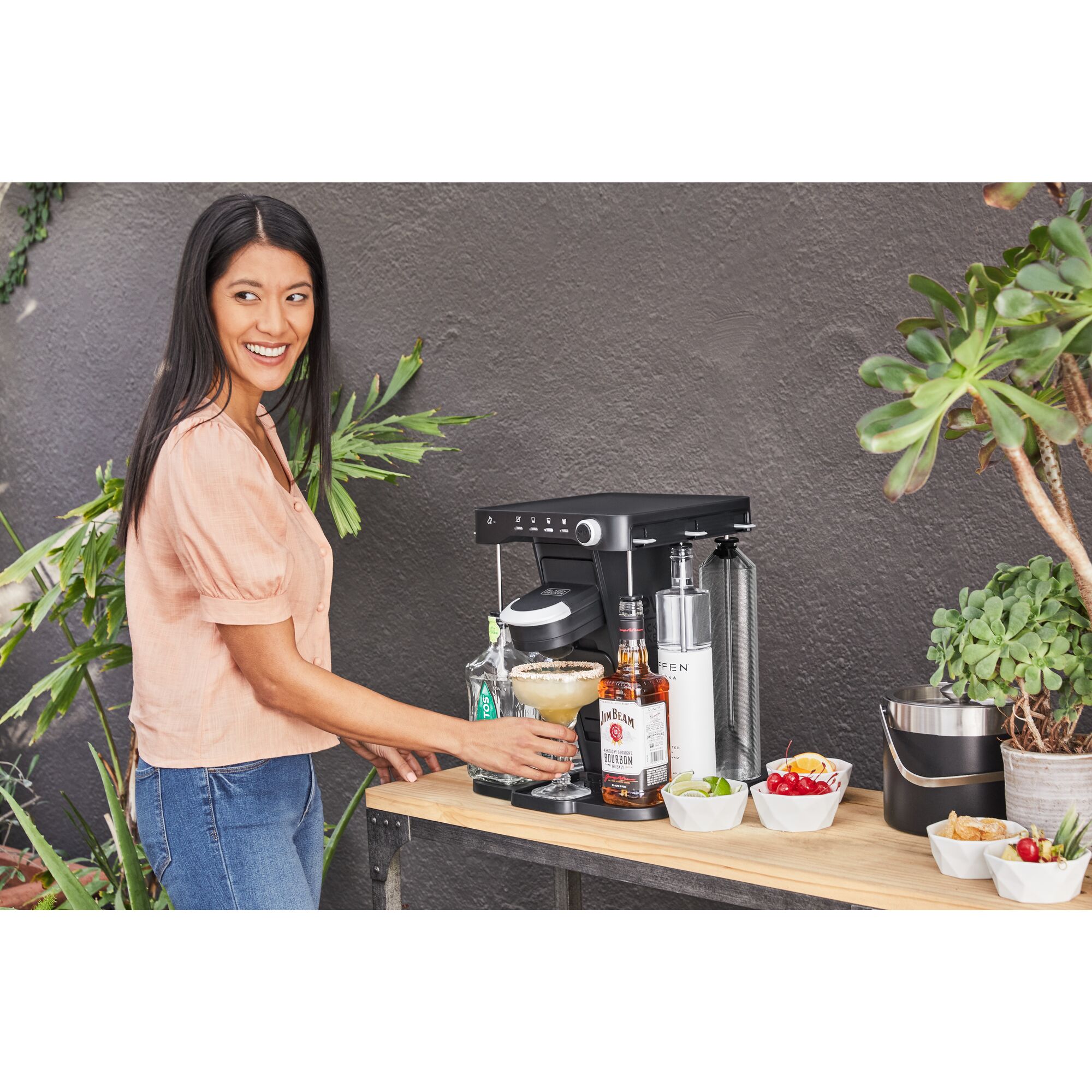 woman, on the patio, picking up the margarita she just made using the bev by BLACK+DECKER\u2122 cocktail maker