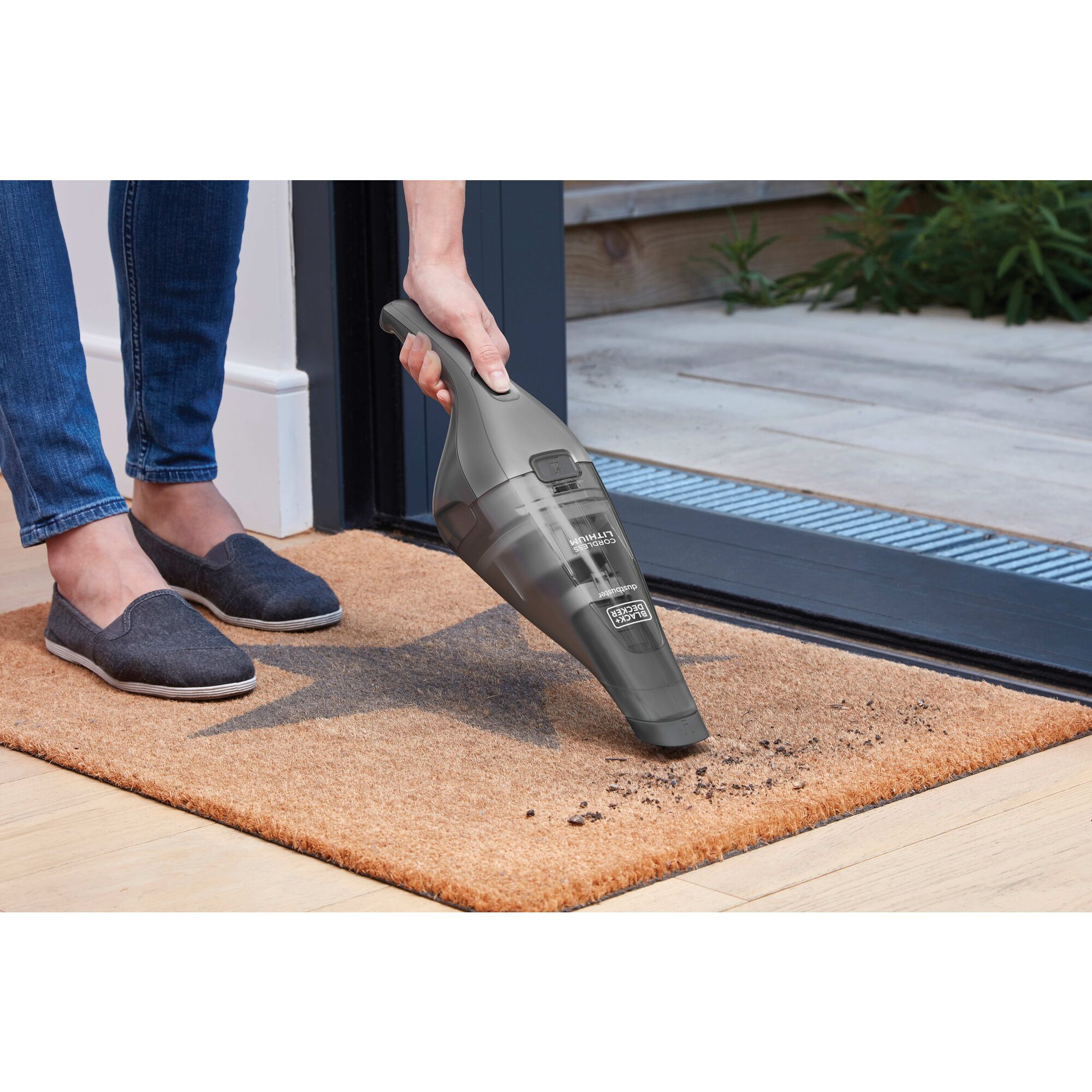 Woman using dustbuster on a welcome mat