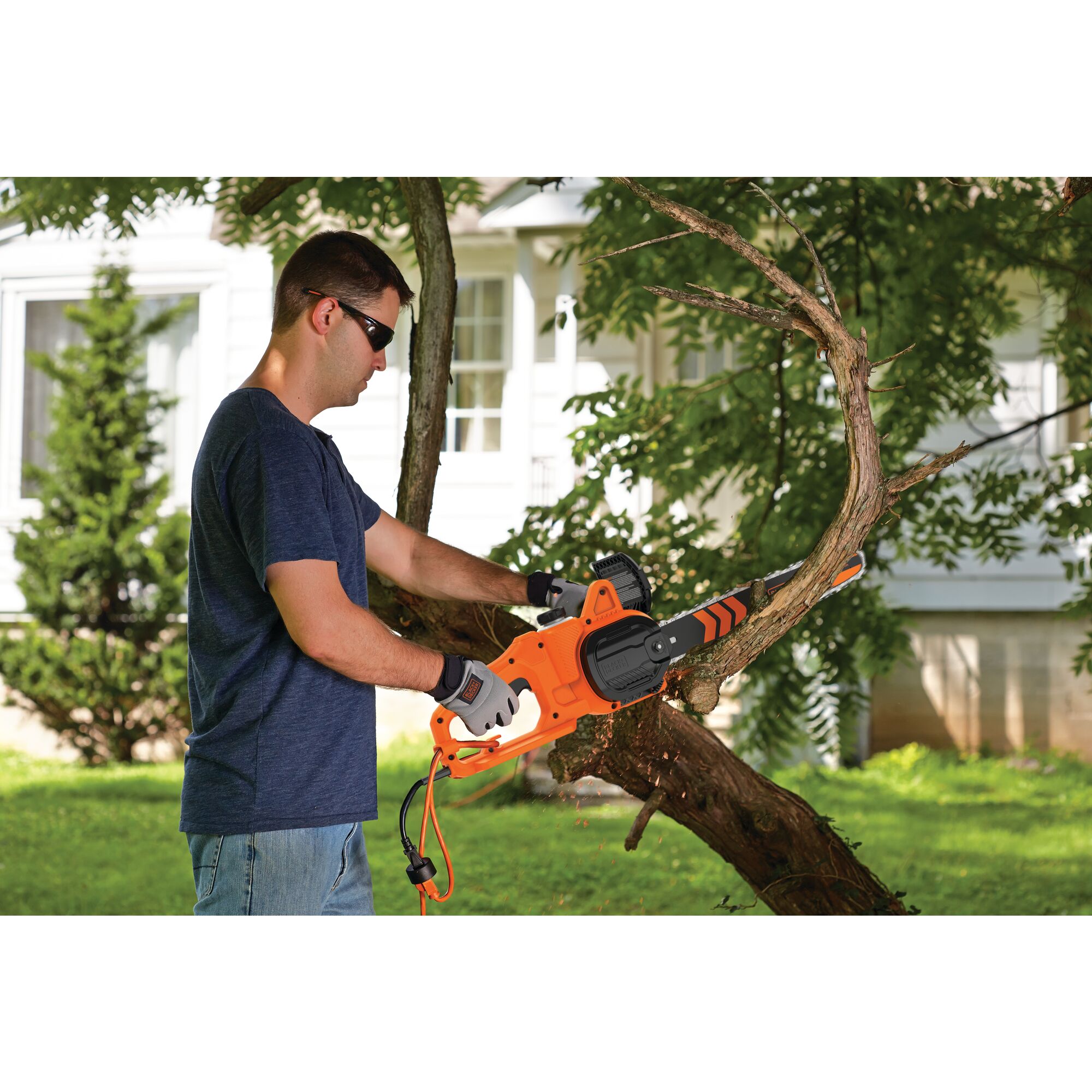 8 Ampere 14 inch Electric Chainsaw being used by person to cut tree branch outdoors.