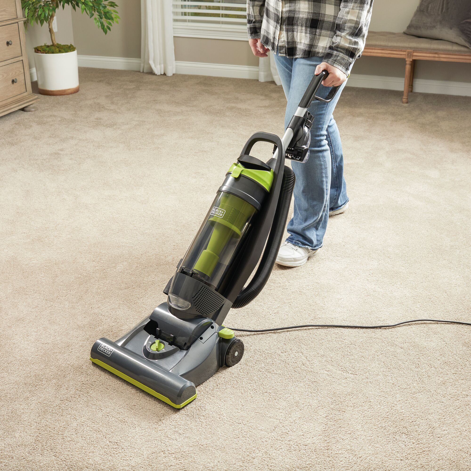 Person using the BLACK+DECKER upright vacuum on a living room floor of carpet