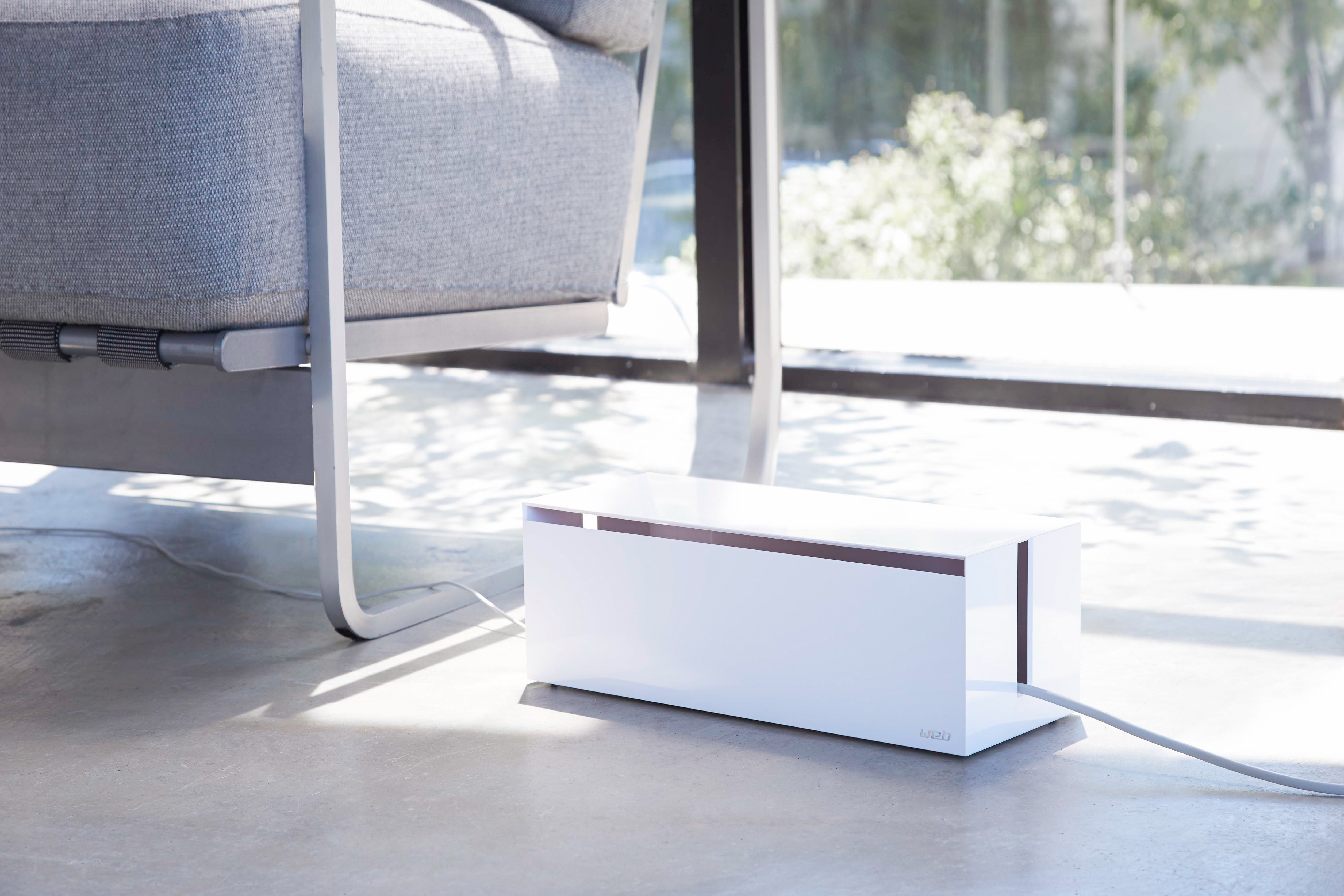 Front view of white Yamazaki Home Cable Management Box holding wires in living room.