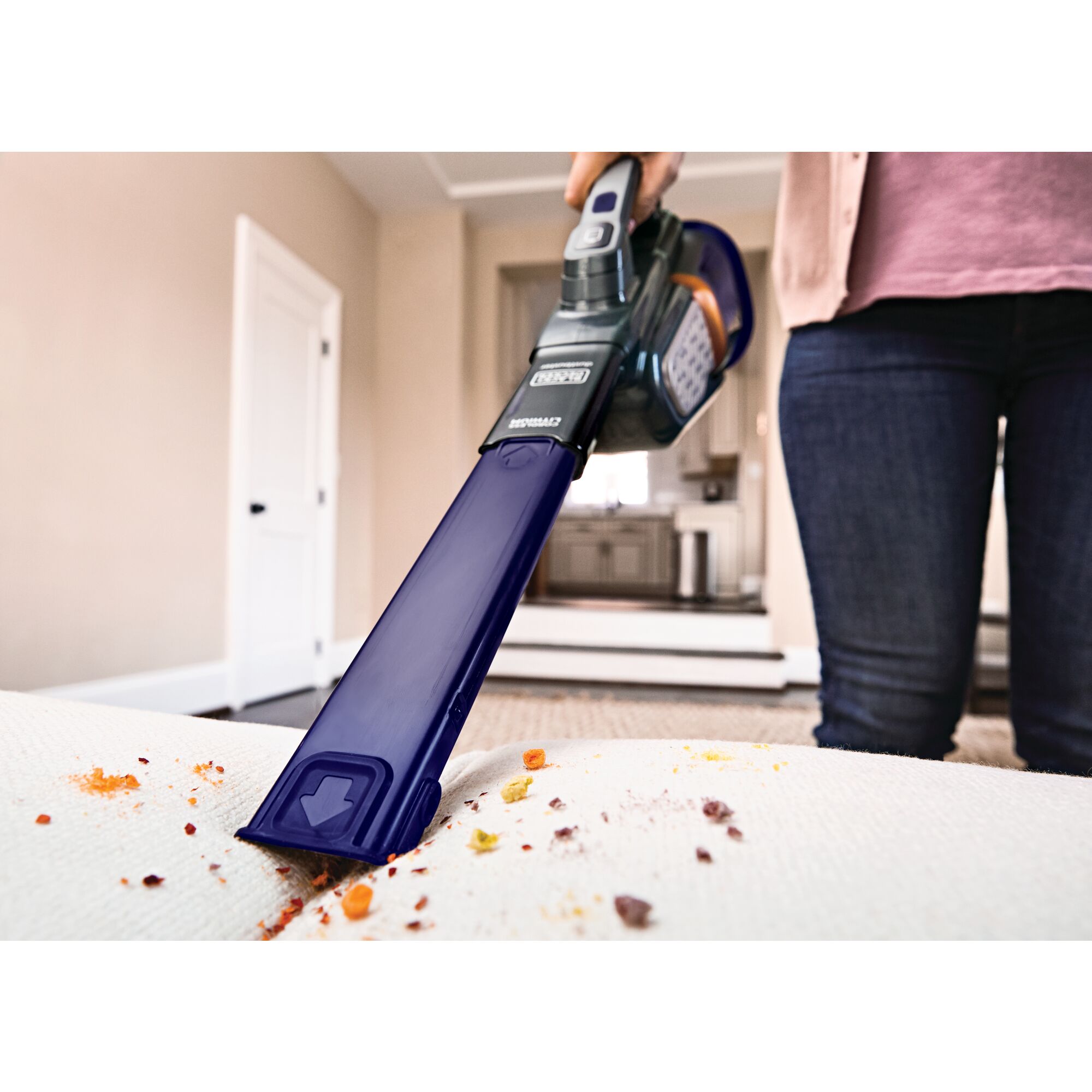 20 volt MAX dustbuster Advanced Clean pet hand vacuum with base charger and extra filter being used to clean debris on sofa.