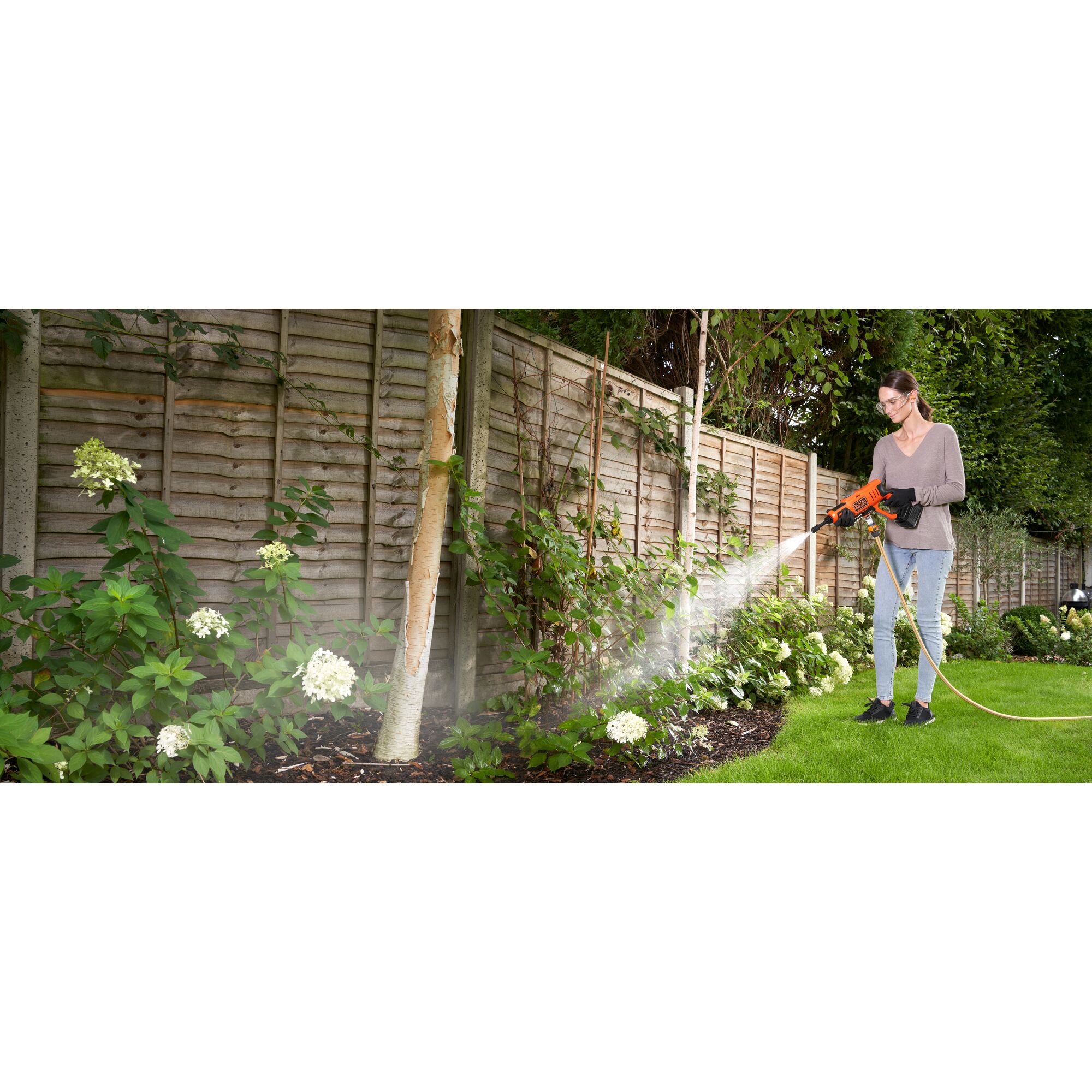 20 volt MAX cordless power cleaner kit being used by a person to water plants in the garden.