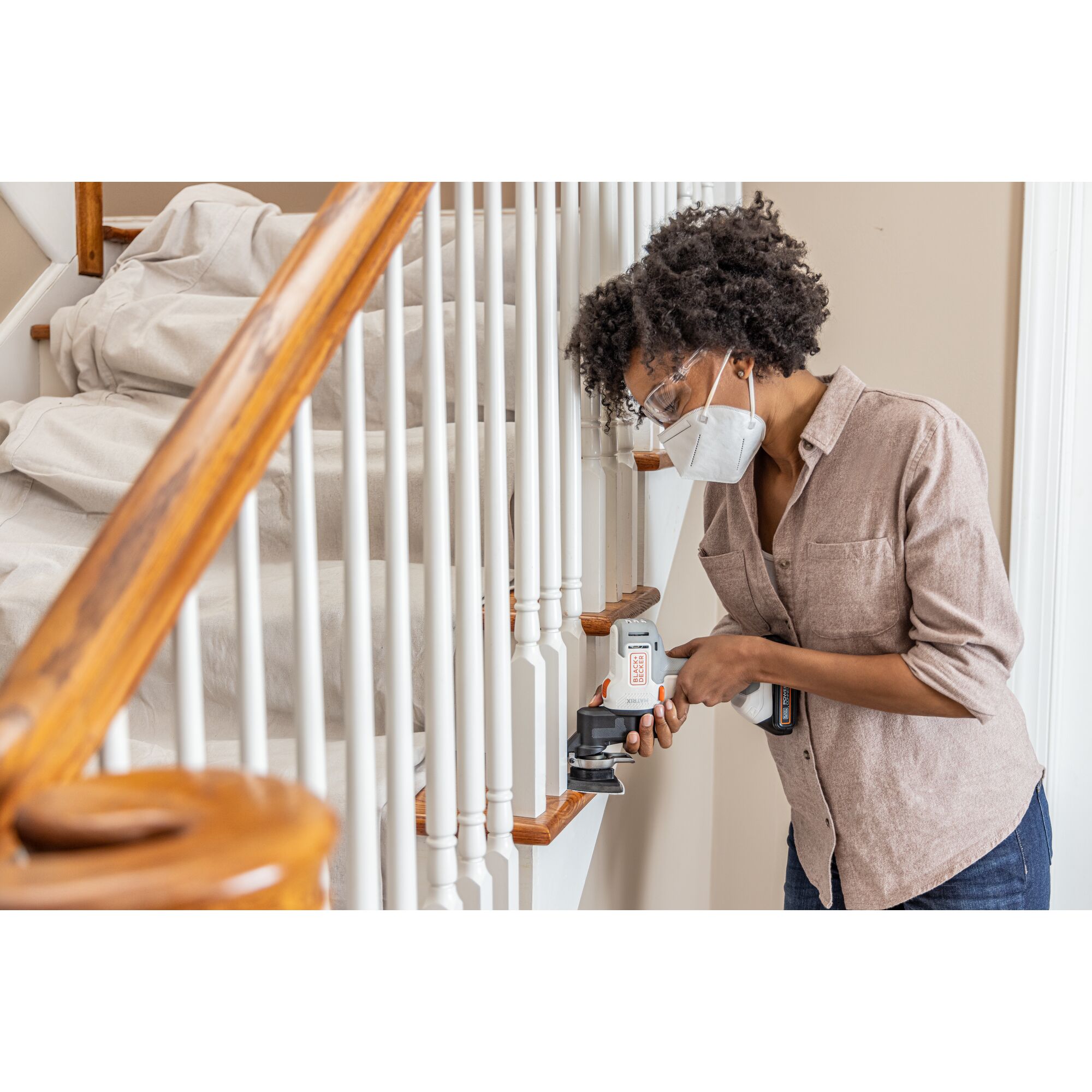 Person sands in between spindles on a staircase with the BLACK+DECKER MATRIX multi-tool attachment