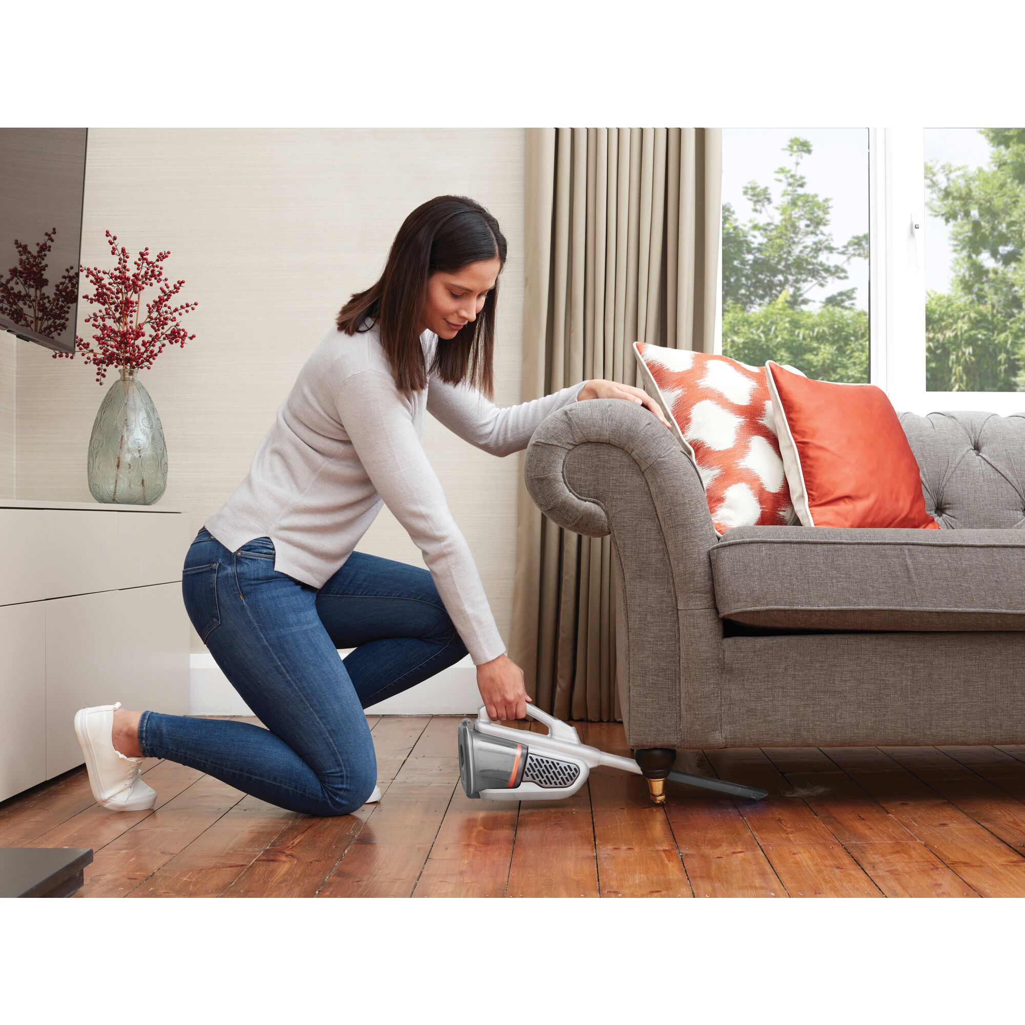 12 Volt dust buster Advanced Clean plus Cordless Hand Vacuum being used by a person under a sofa.