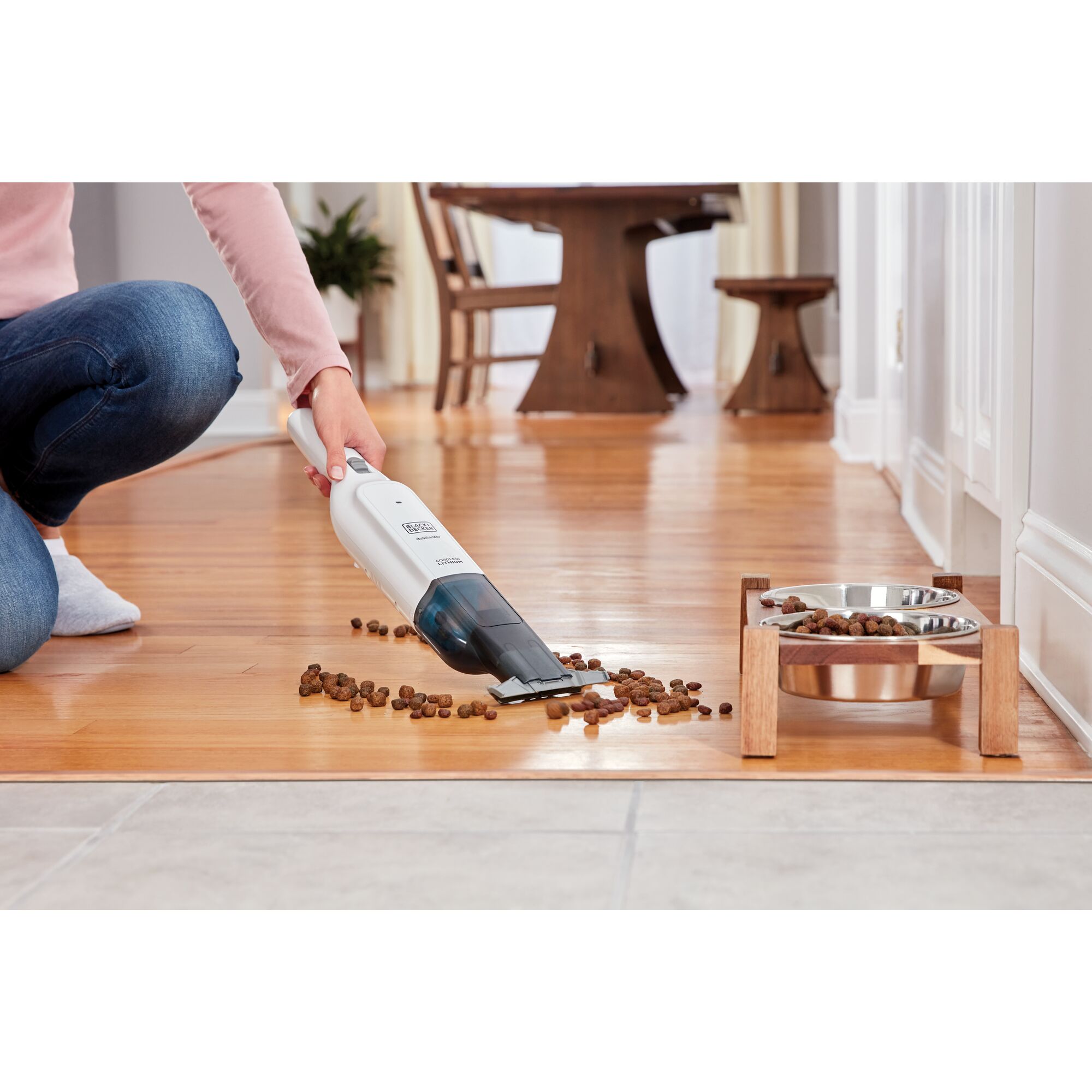 dustbuster AdvancedClean slim cordless handheld vacuum being used by a person to clean cat food spillage.\n