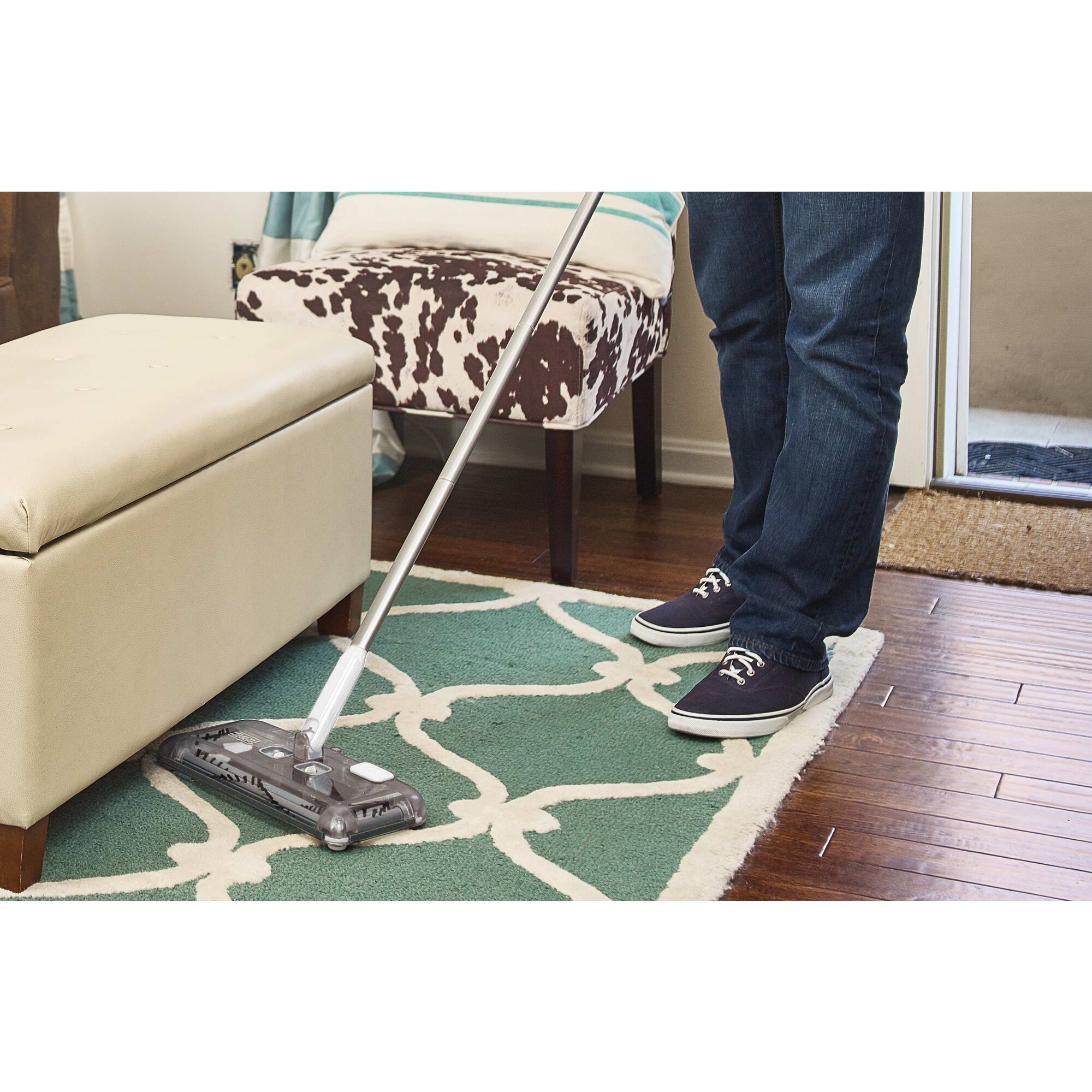Person using black and decker 50 Minute Powered Floor Sweeper to clean rug