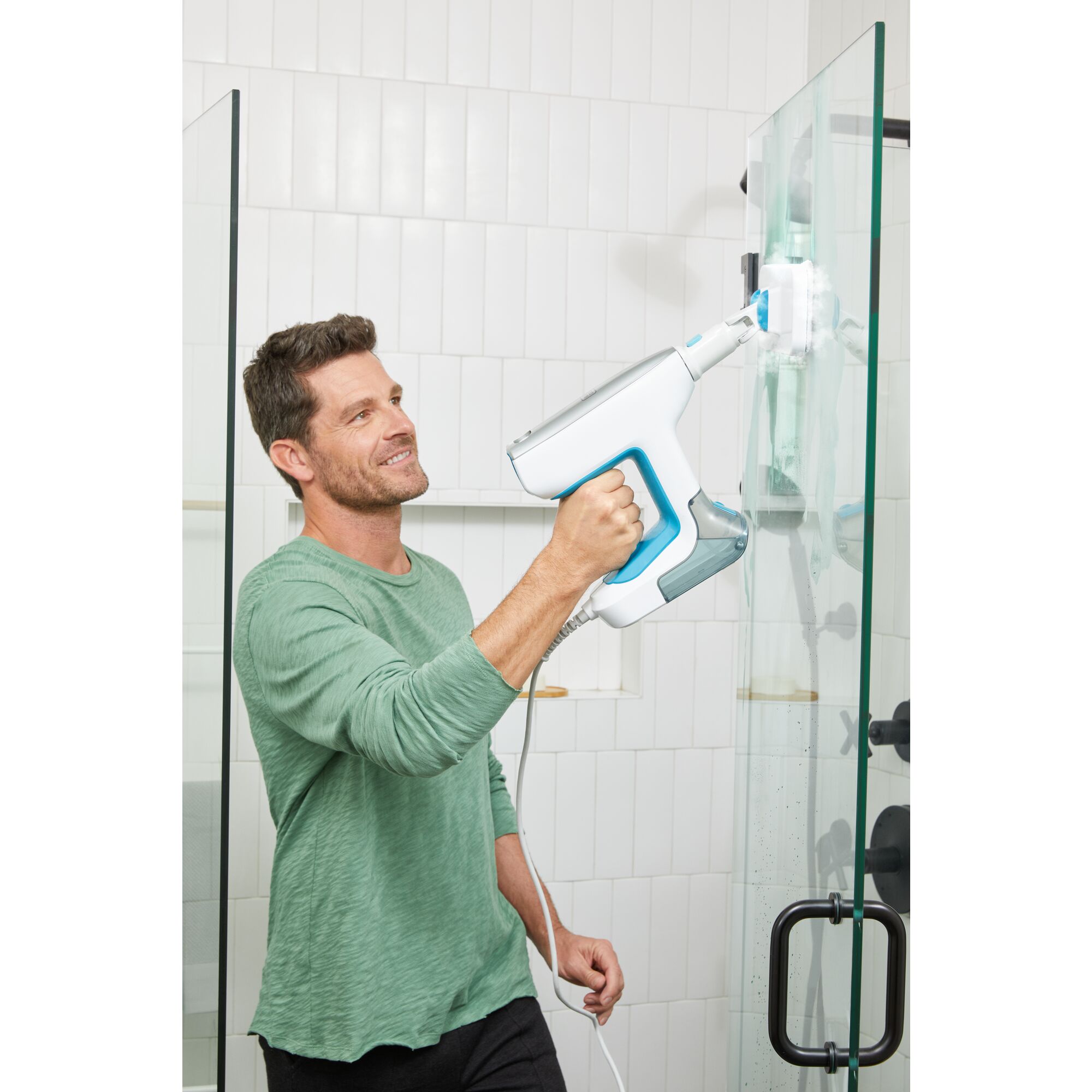 Man cleaning shower door with steam mop accessory