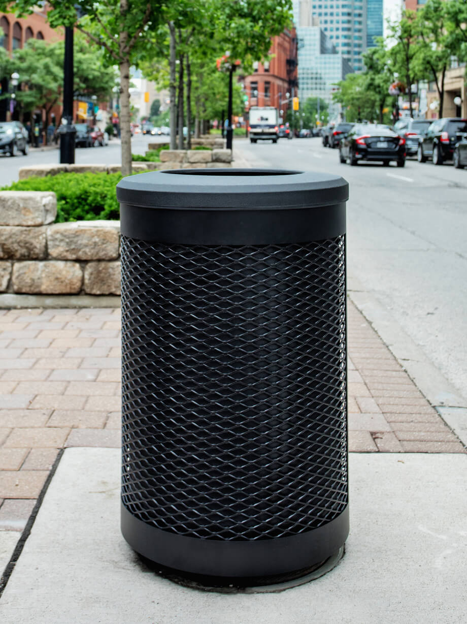 black powder coated steel waste bin body with black LDPE plastic lid and liner sitting on a city street