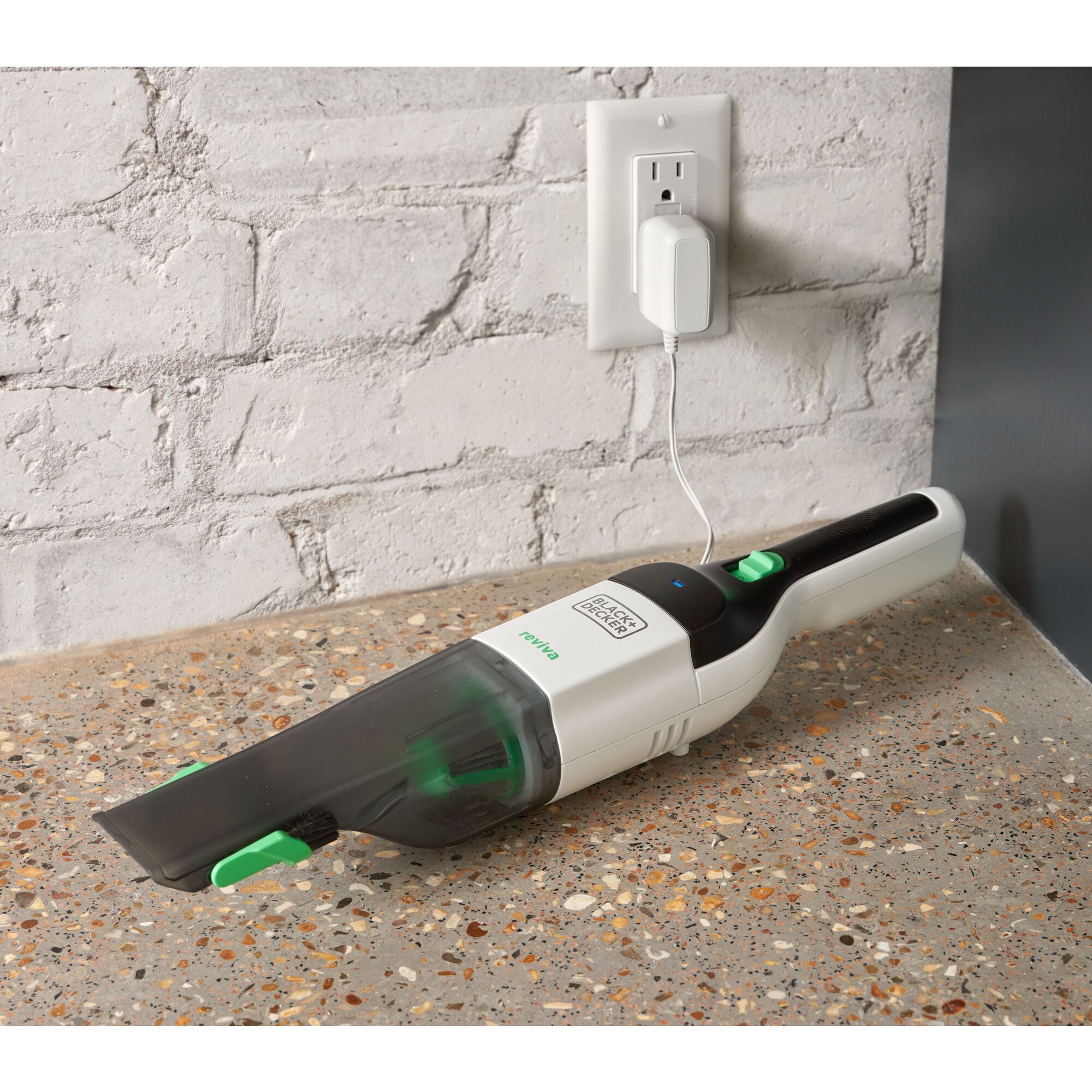 BLACK+DECKER reviva hand vac charging on a counter plugged into an outlet.