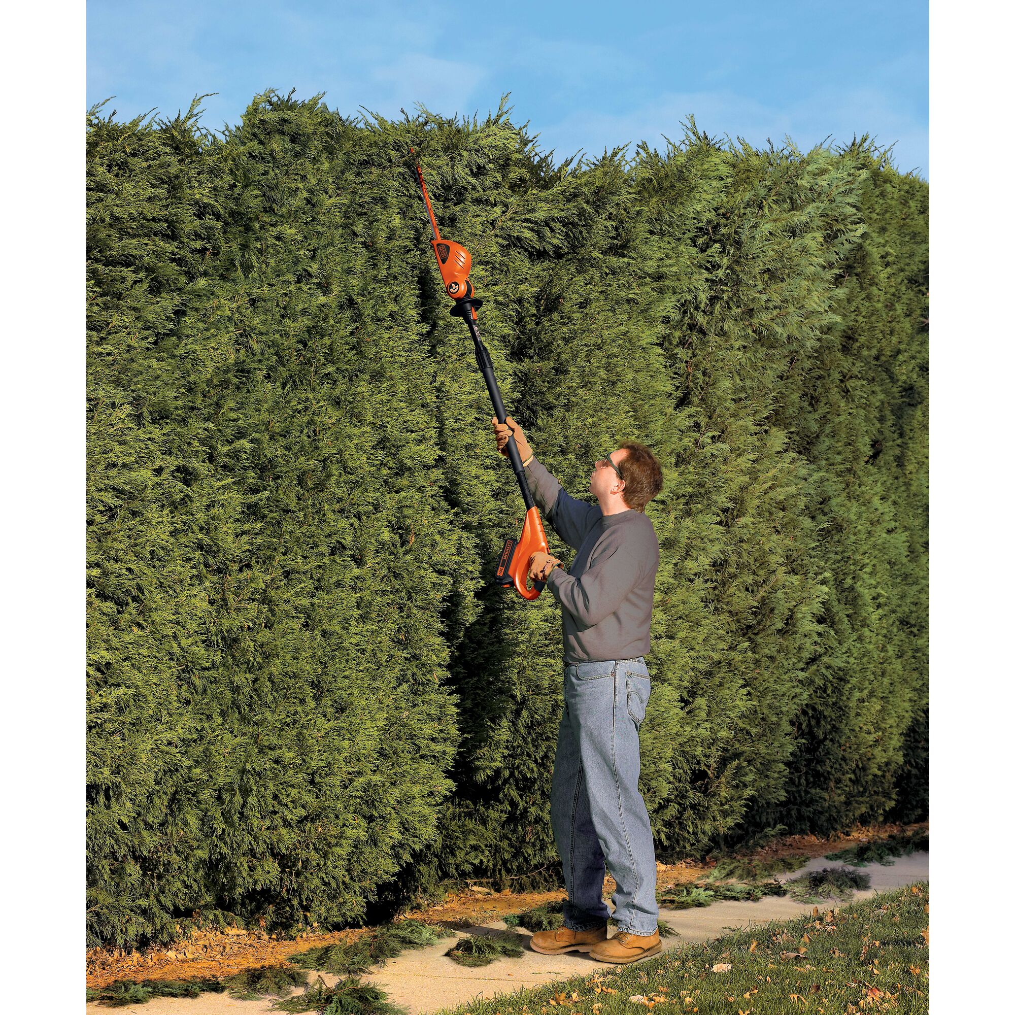 MAX Lithium Pole Hedge Trimmer being used by person to trim long heighted shrubs outdoors.