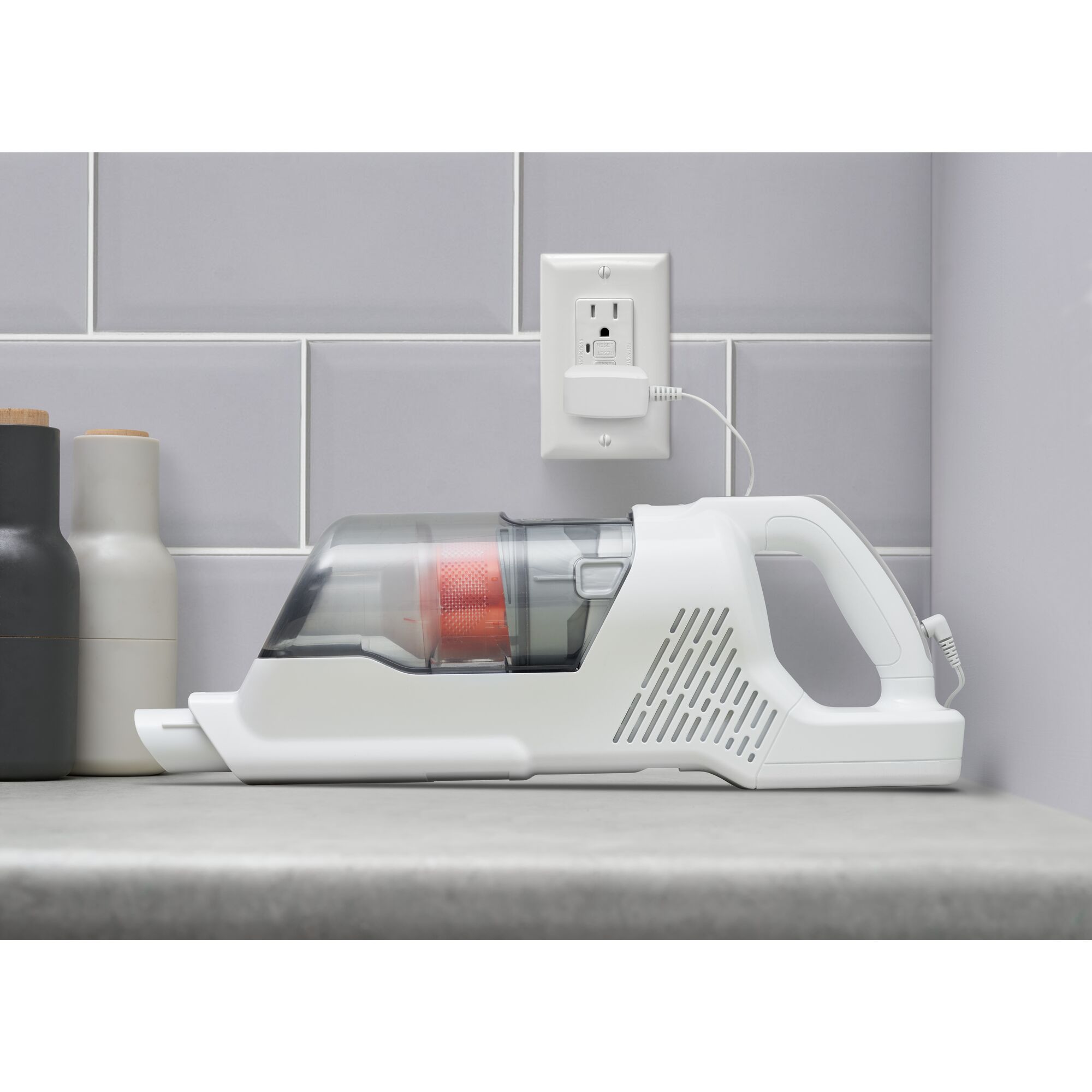 Handheld portion of Black and decker power series plus cordless stick vacuum plugged into charger on a countertop.