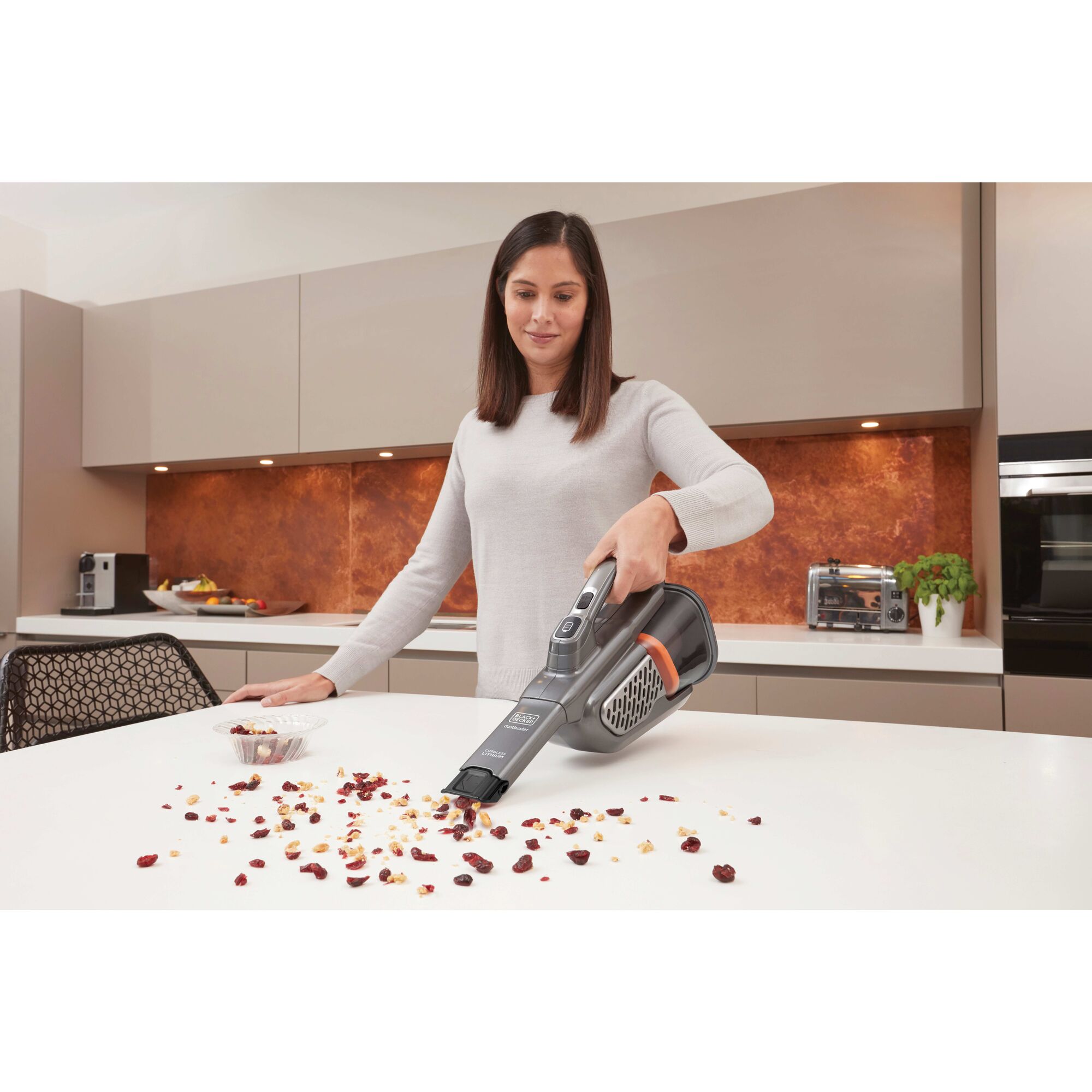 Dustbuster advanced clean plus hand vacuum being used by a person to clean mess on table.