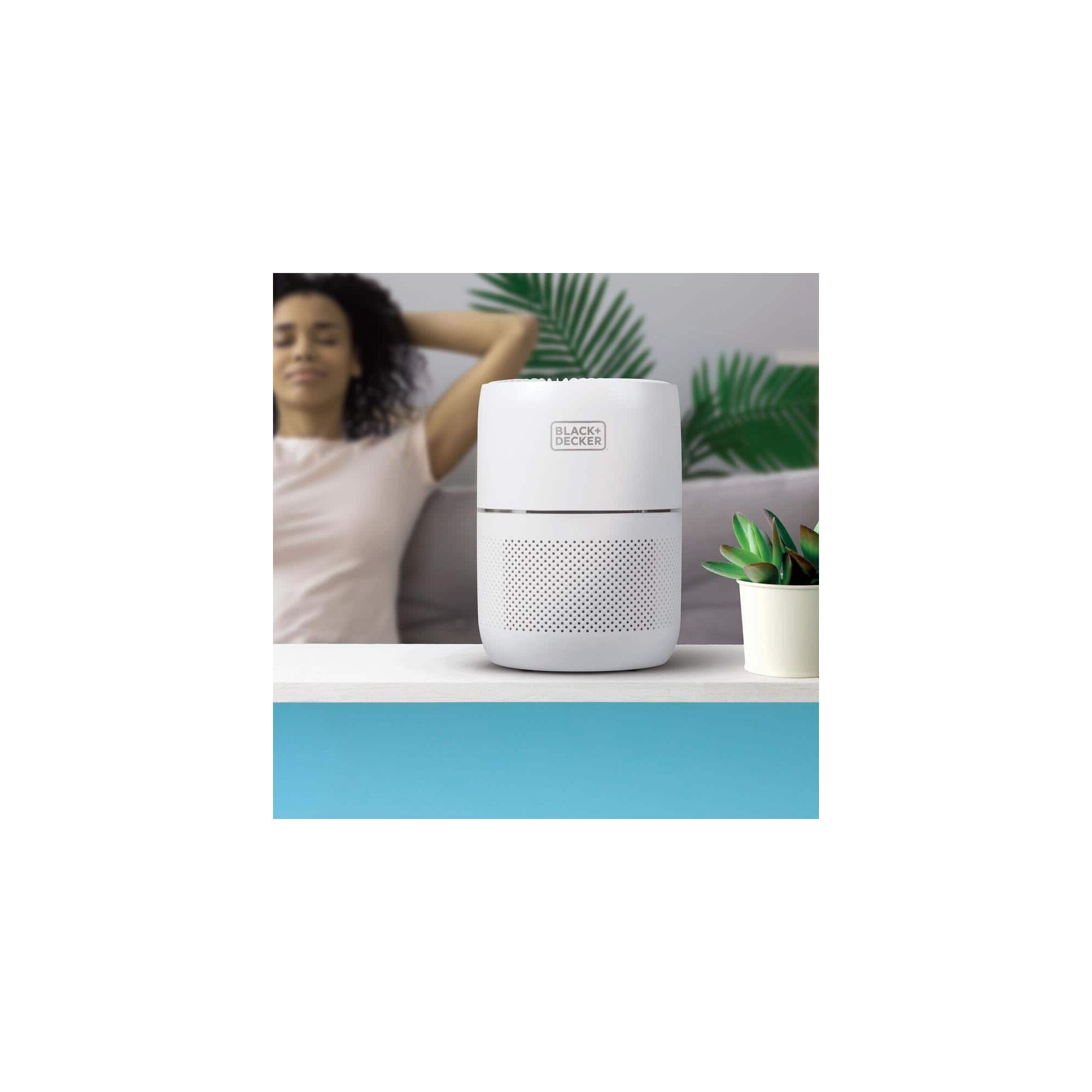 BLACK+DECKER Hepa Tabletop Air Purifier on a counter near a woman relaxing in the background