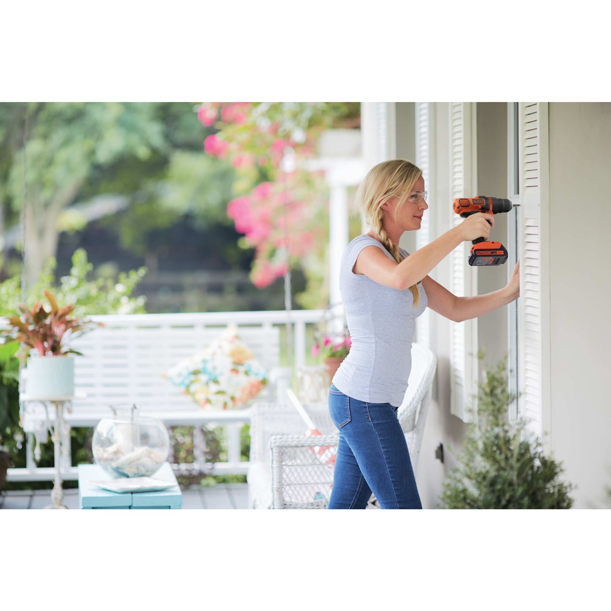 Person using a BLACK+DECKER 20 volt max Powerconnect cordless drill driver to attach a white shutter to a house