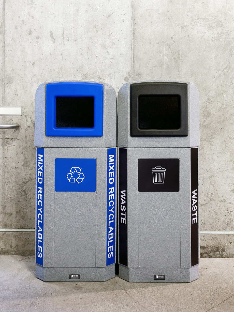 double recycling and waste collection station with color coded openings and large labels at a busy transit station