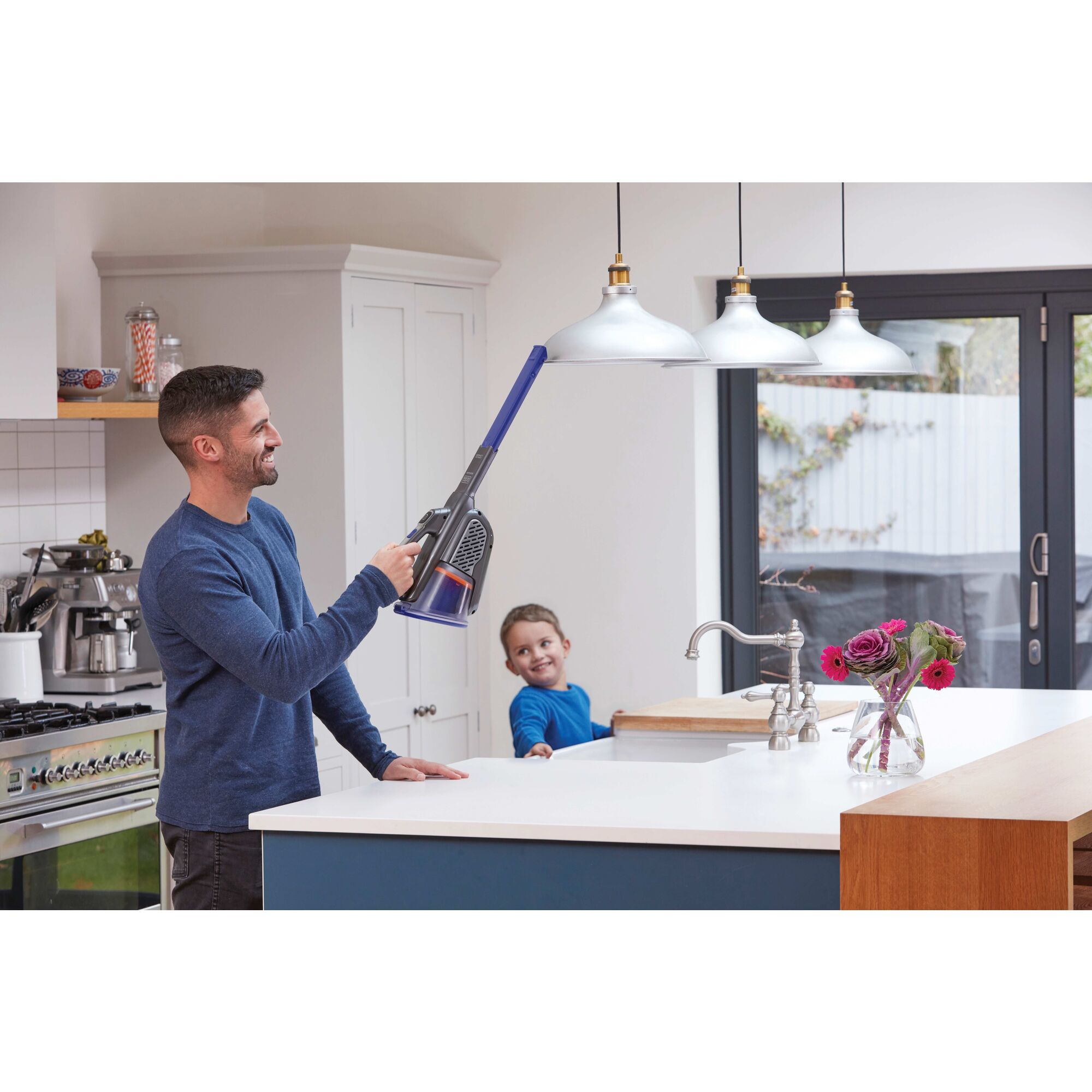 dustbuster AdvancedClean pet cordless hand vacuum being used by a person to clean hanging light shades.
