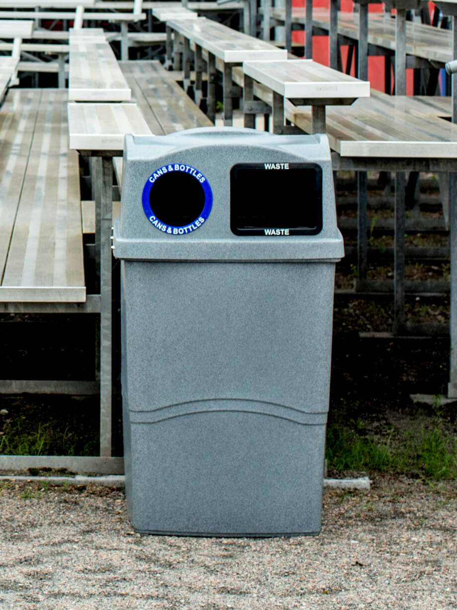 cans and bottles recycling and waste bin with a durable grey body and lid beside sports bleachers at a baseball field