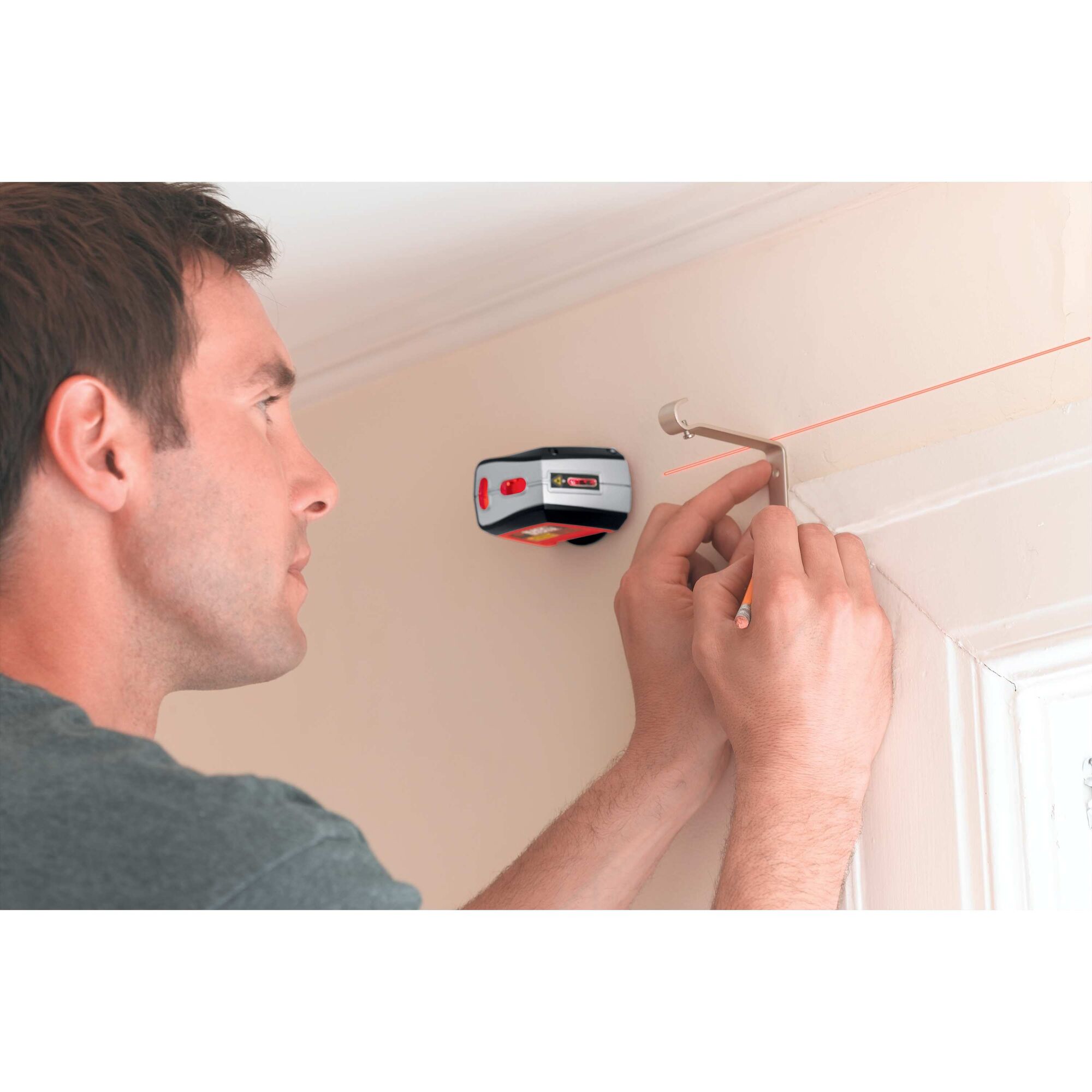 Laser level being used by a person to perfectly fix curtain rod attachment.